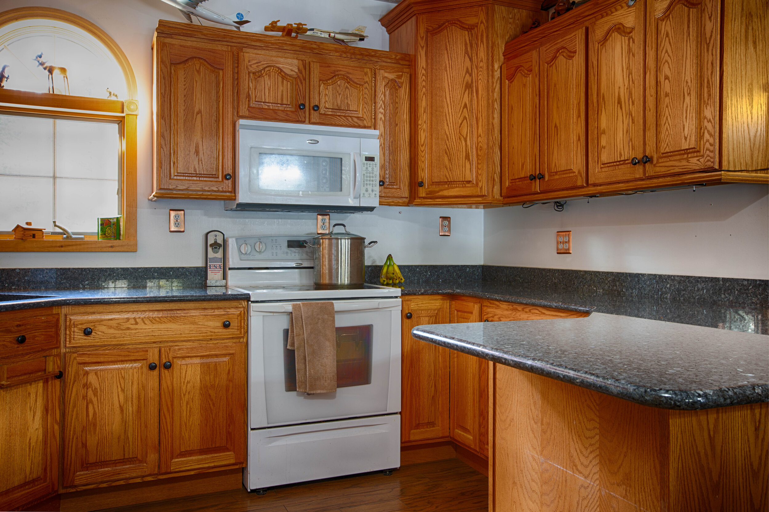 kitchen view of stove, microwave and wooden drawers and cabinets