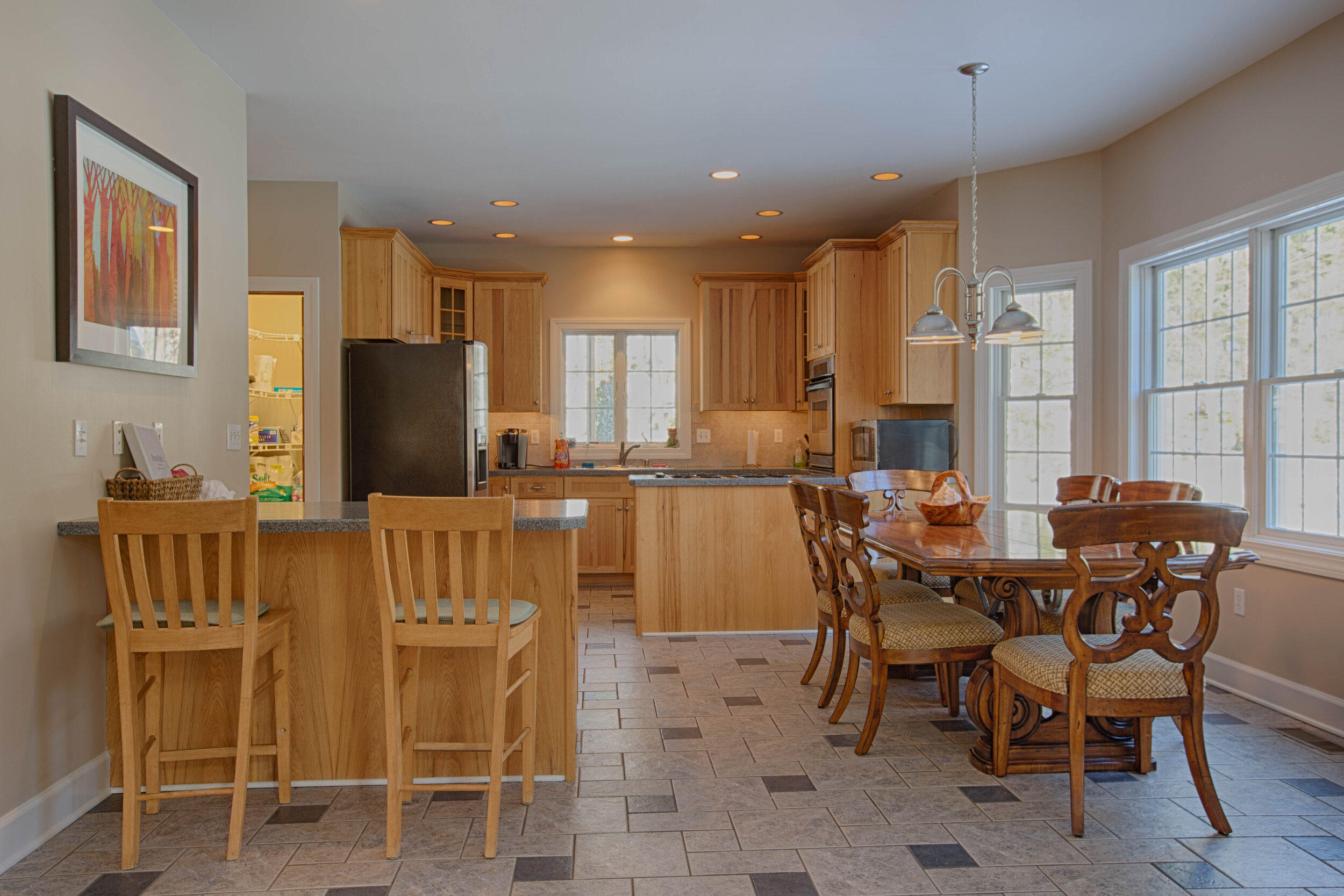  Open concept kitchen.  This kitchen shows a bar/island with stools for sitting, Kitchen table to the right fo adding seating next to windows for an outside view. 