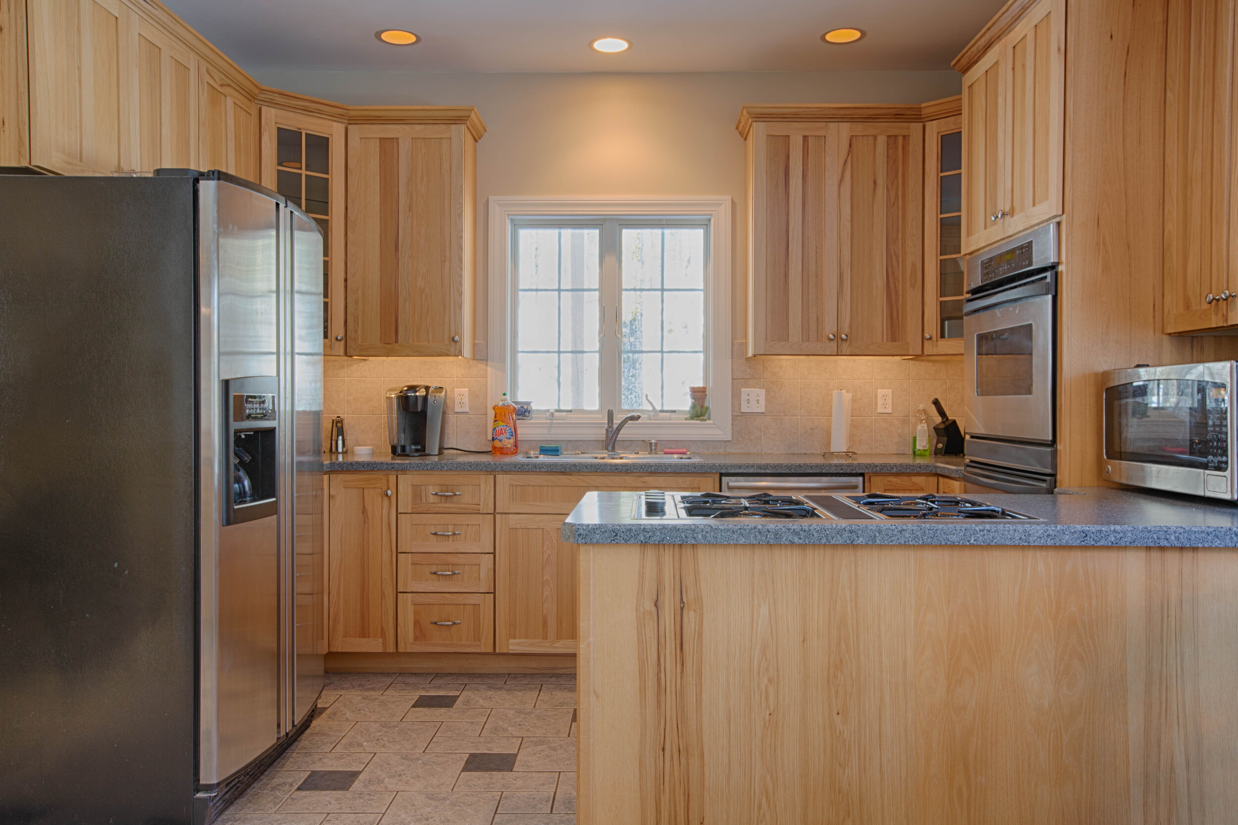  Kitchen with French, stainless steel refrigerator.  Tall cabinets and an island with cooktop. 