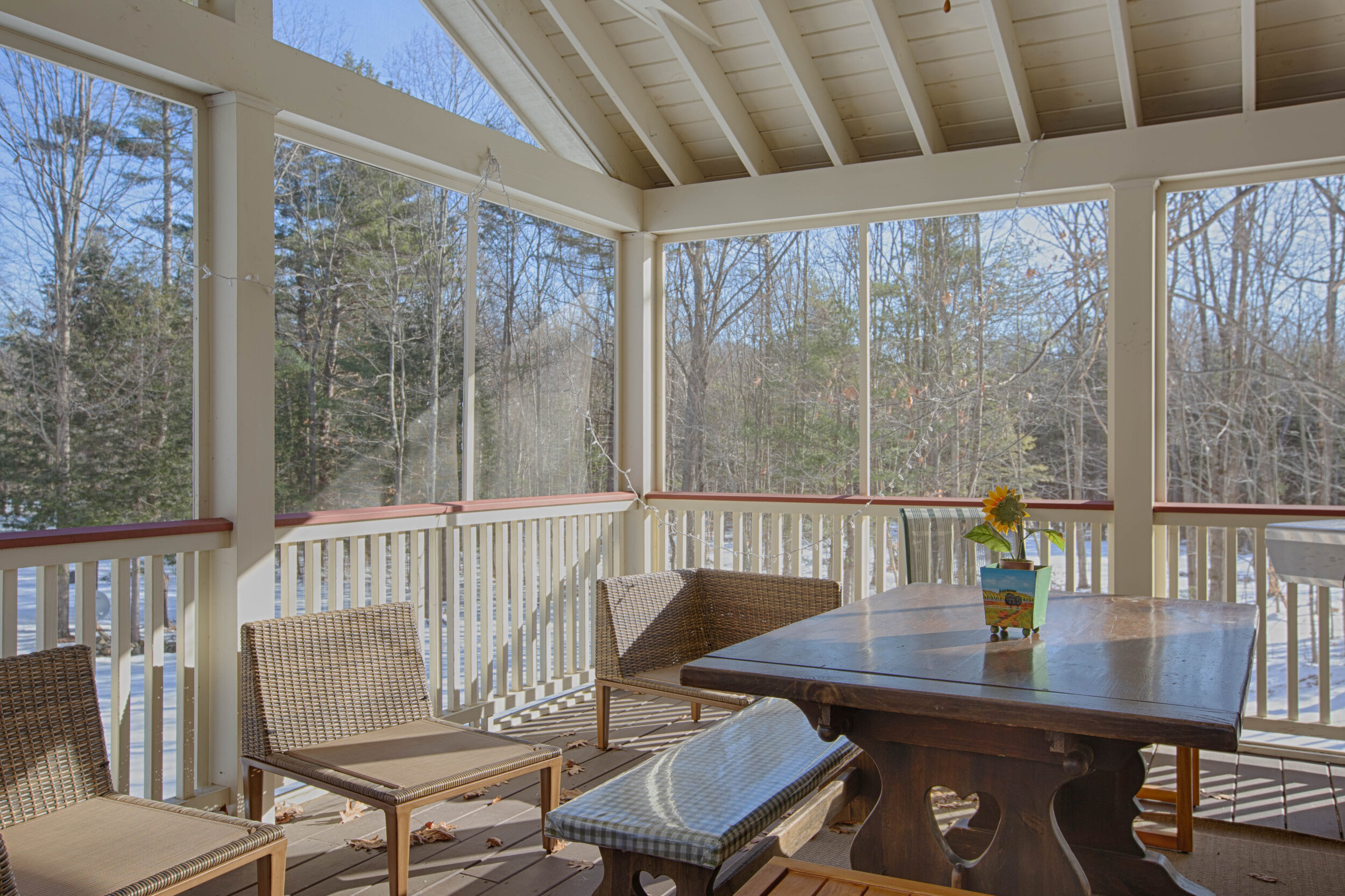  Screened in porch with table in the center with chairs. 