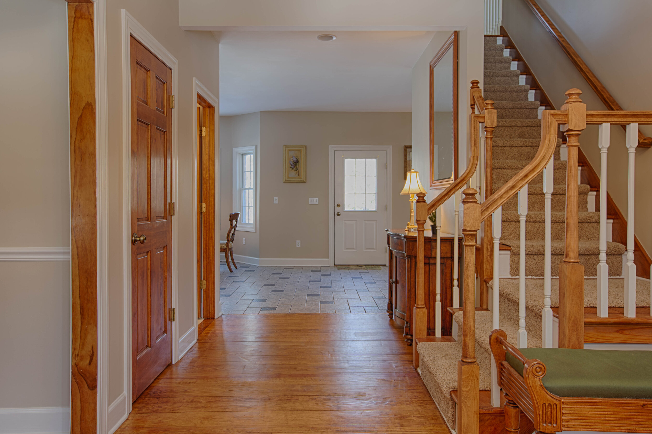  Picture of the hallway with closet door to the left and staircase to the right.  In front leads to the dining room/kitchen area. 