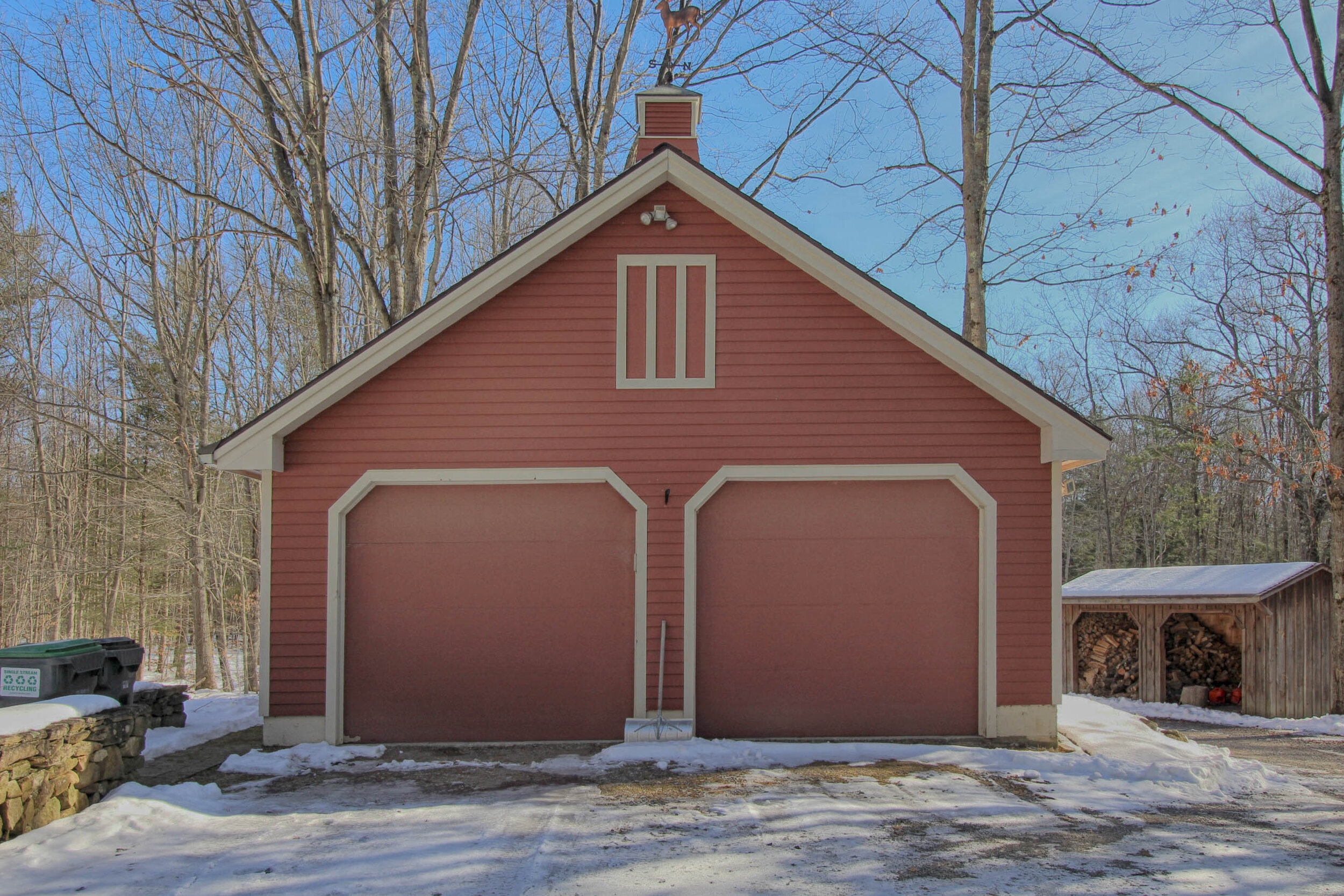  Red barn looking double garage with white door trim around the garage doors. 