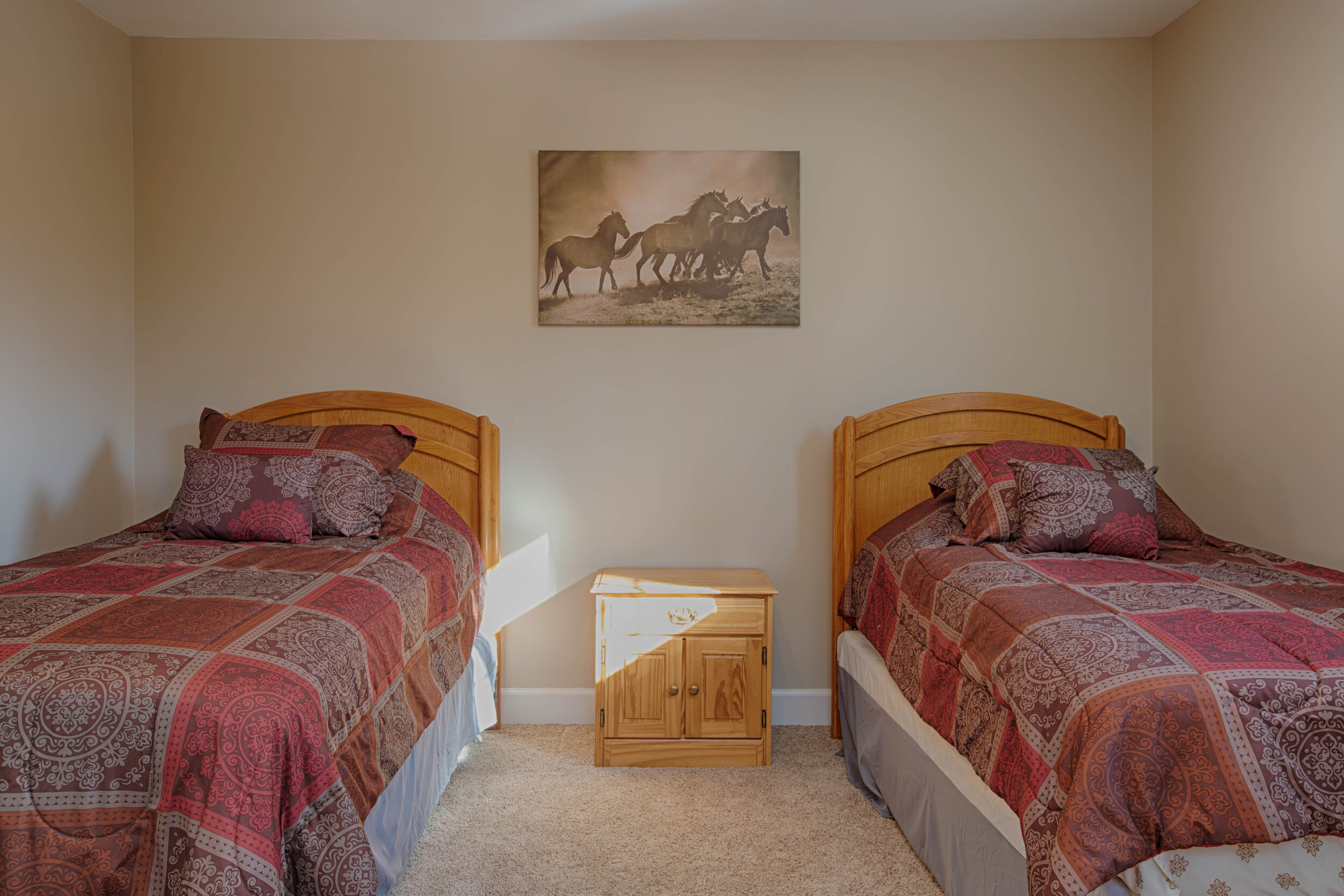  Another bedroom with two twin beds next to one another with a night stand in between to separate them. 