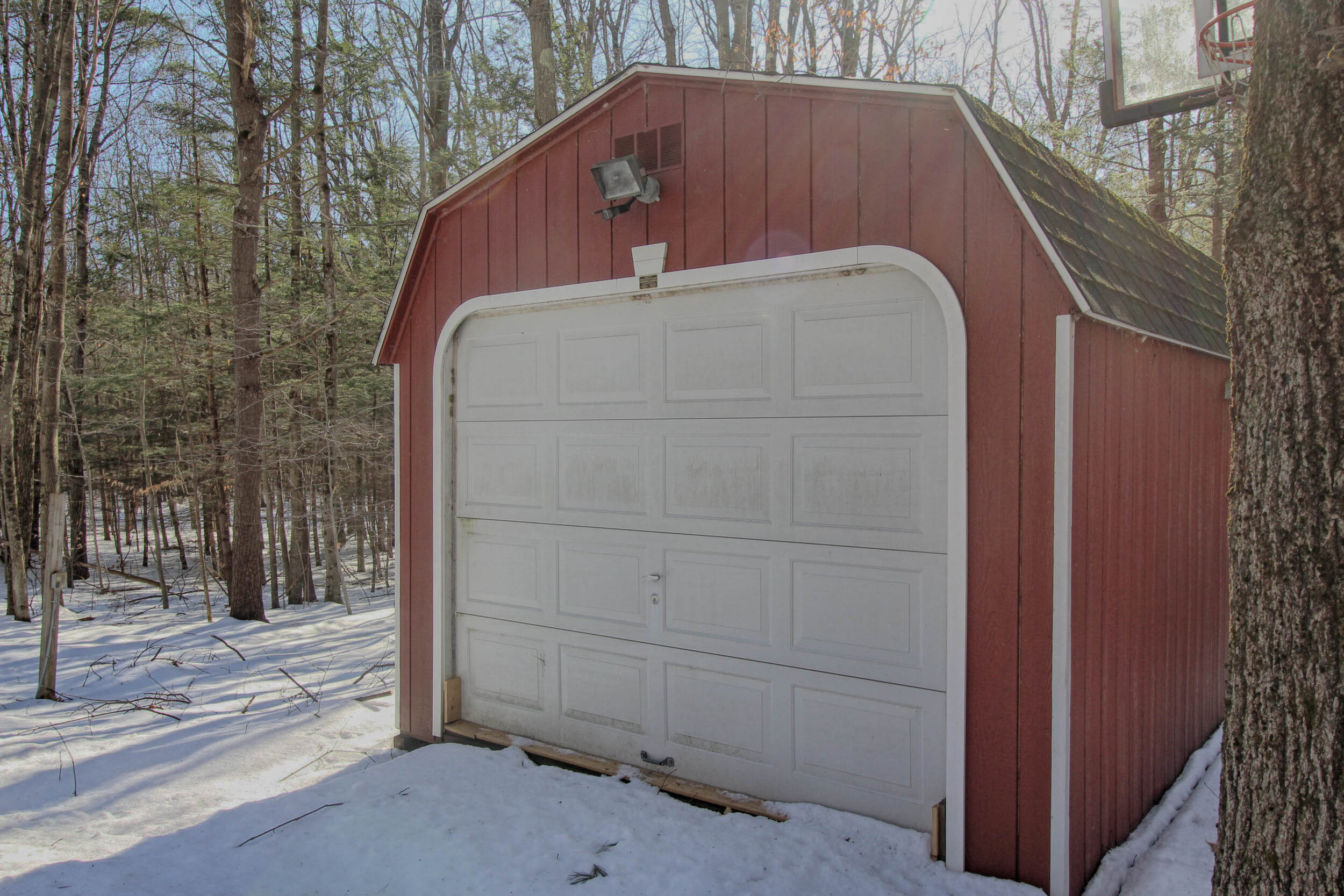  Single, red garage detached from the other garage with white door. 