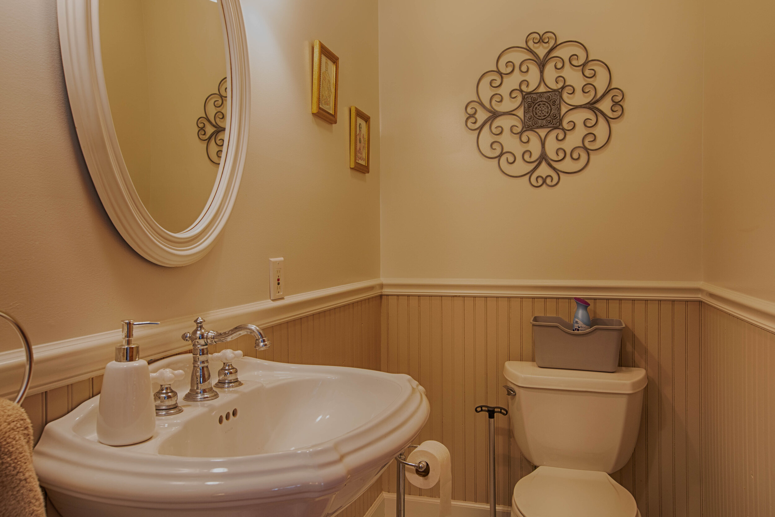  Bathroom with pedestal sink, mirror above and a toilet.   