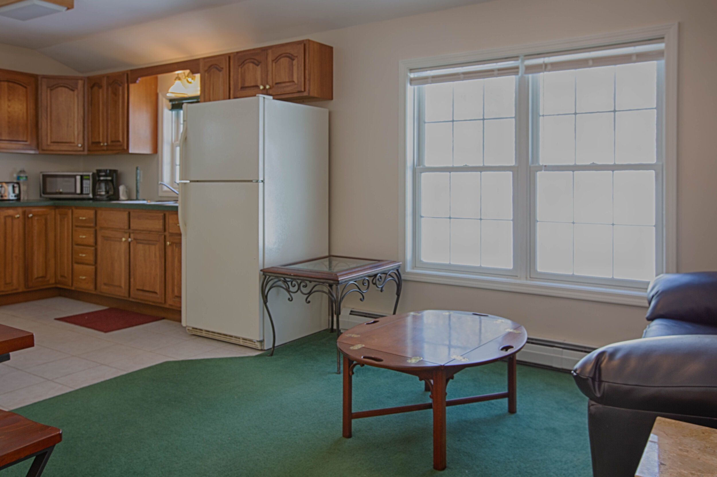  In law suite with green carpet in the living room and white appliances in the kitchen. 