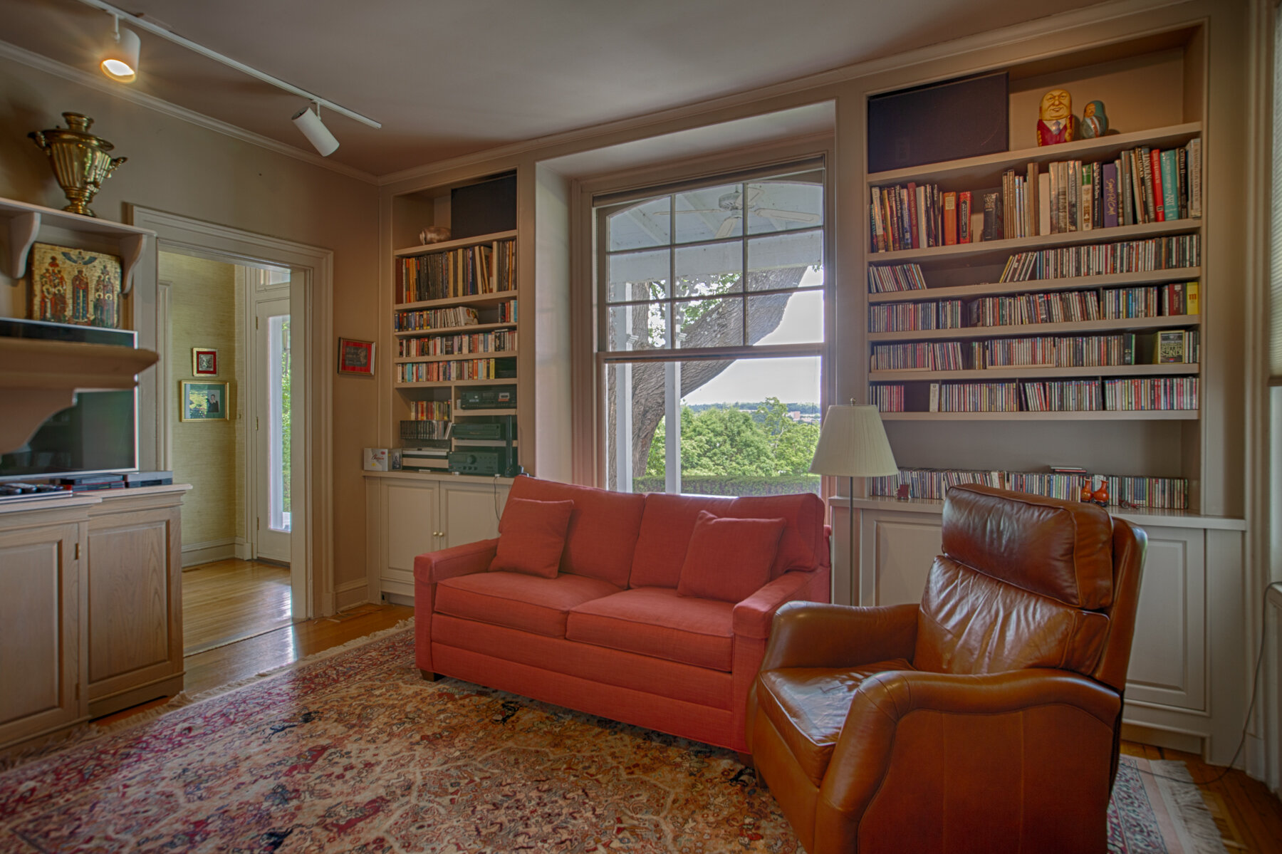  Built ins on the back wall that house many books. Red couch and a leather chair are in this room.. Would make for a great reading room. 