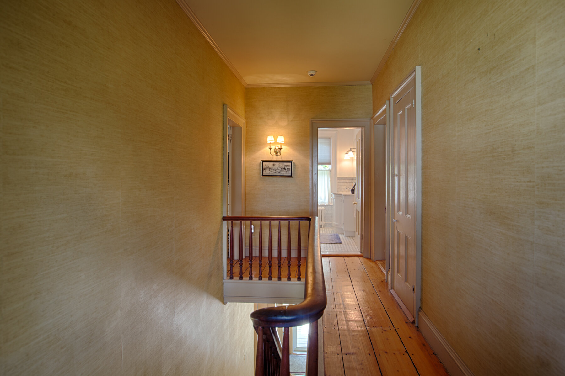  Hallway looking down to the bathroom. Wide wood plank floors leading down the hallway. 