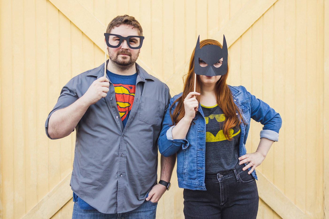couple wears batman and superman props during engagement session