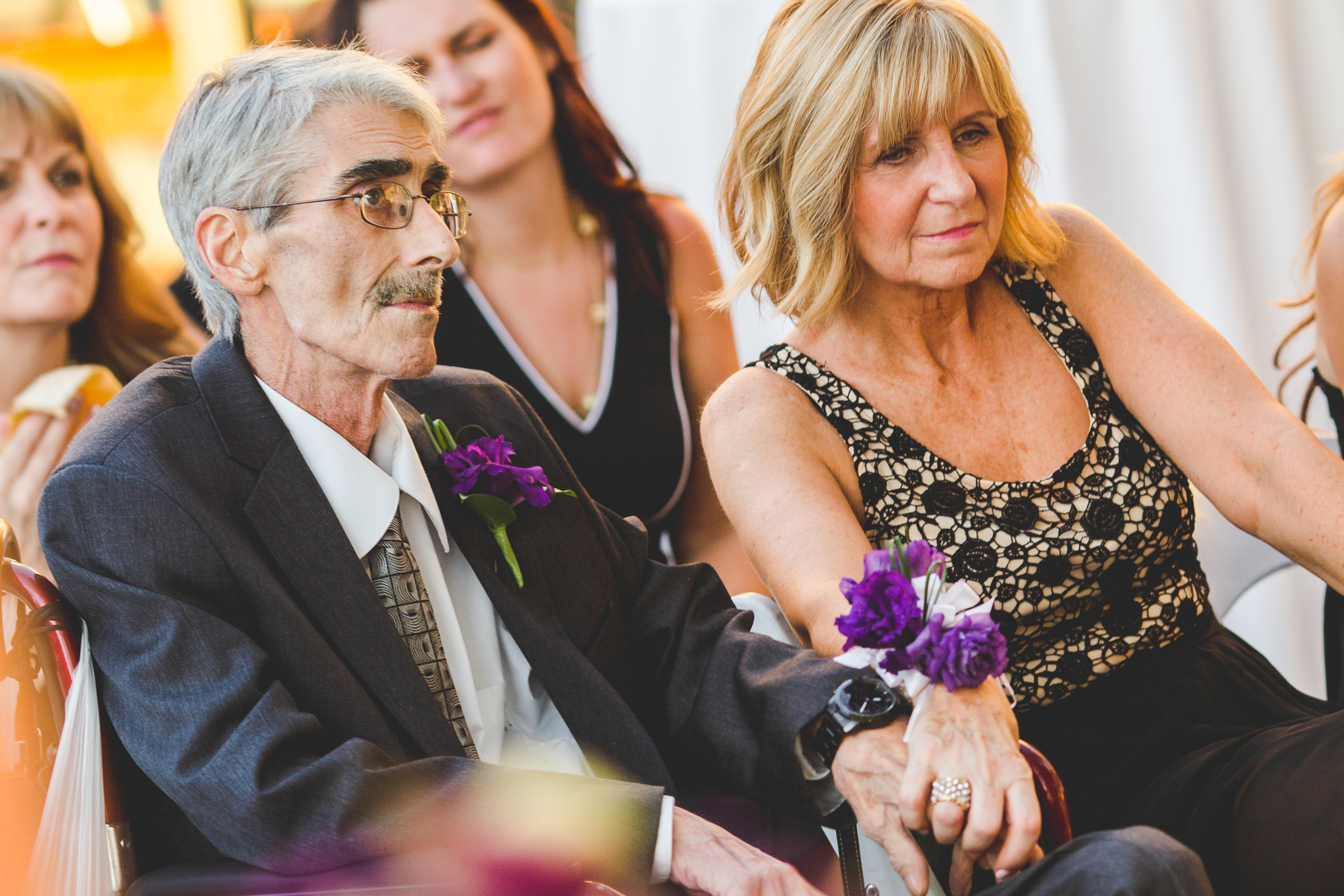 parents of groom hold hands at ceremony lc