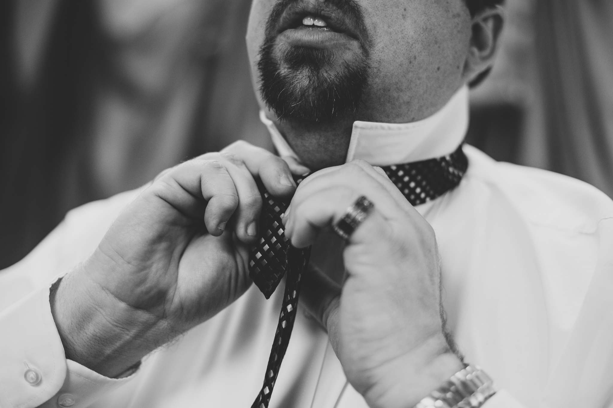 rs groom puts his tie on getting ready bw