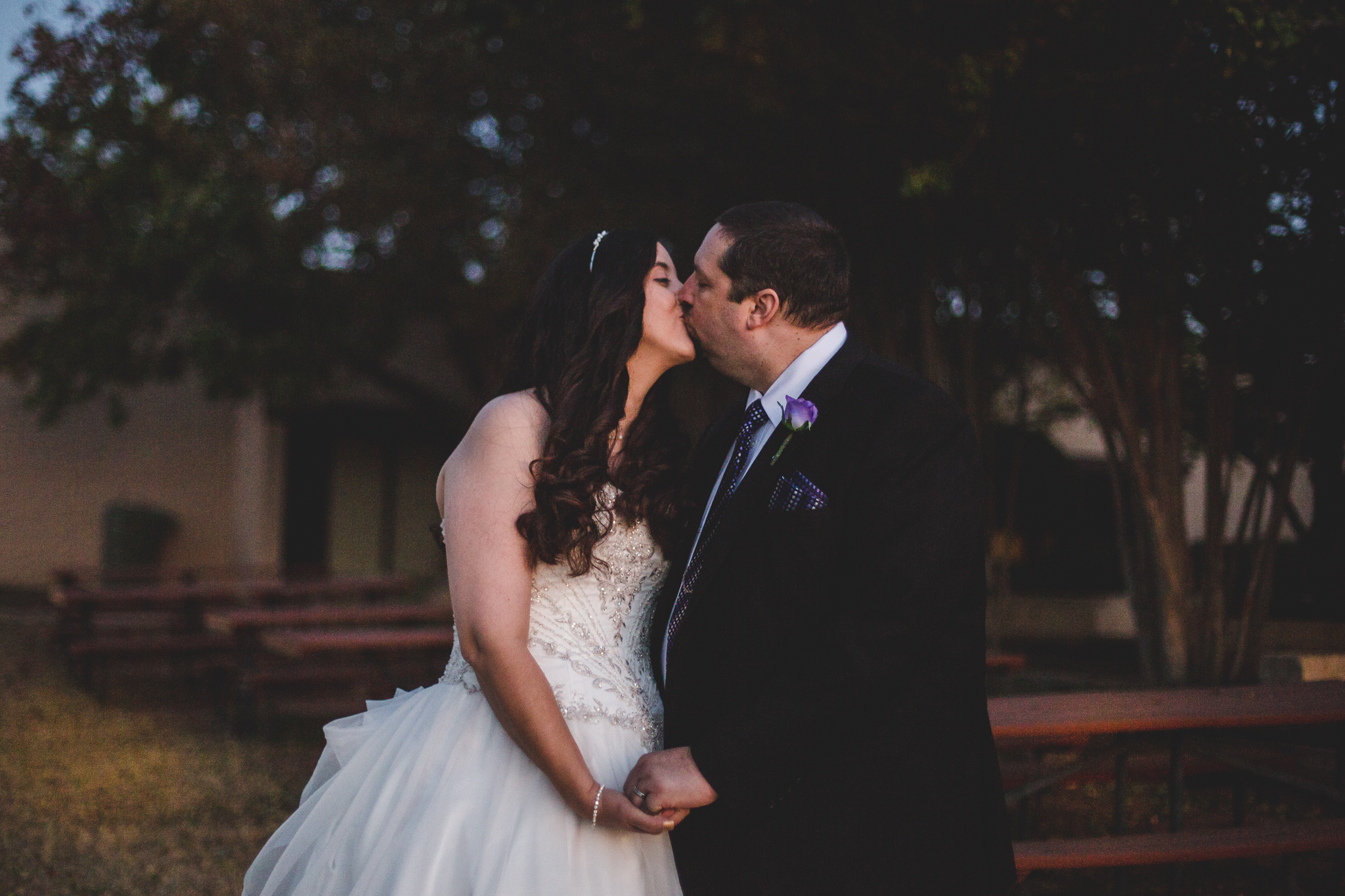 rs bride and portrait groom kiss outside at night