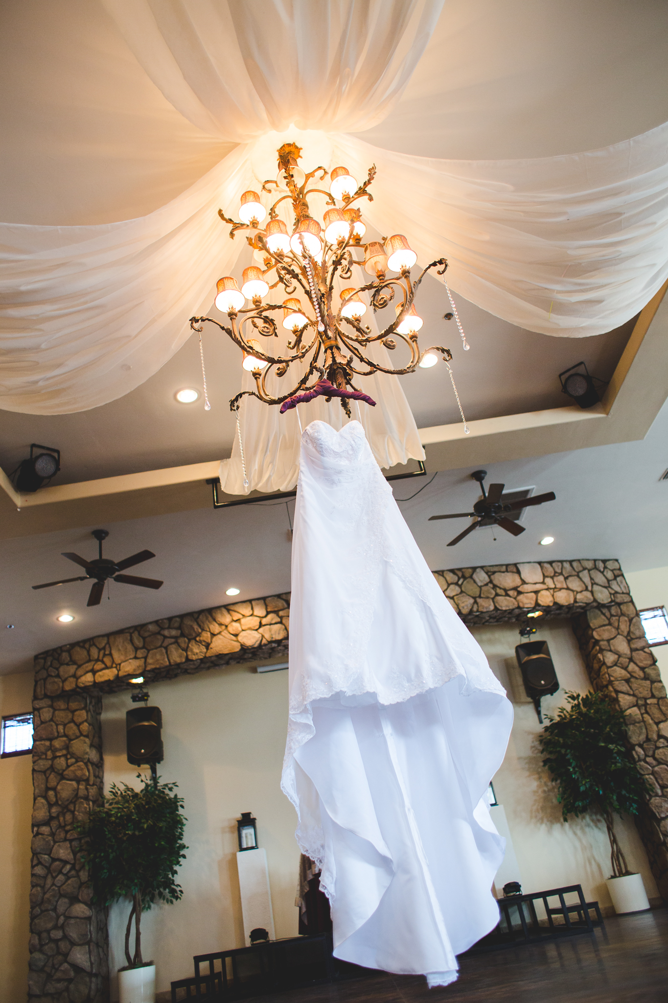 wedding dress detail shot hanging from chandelier mj