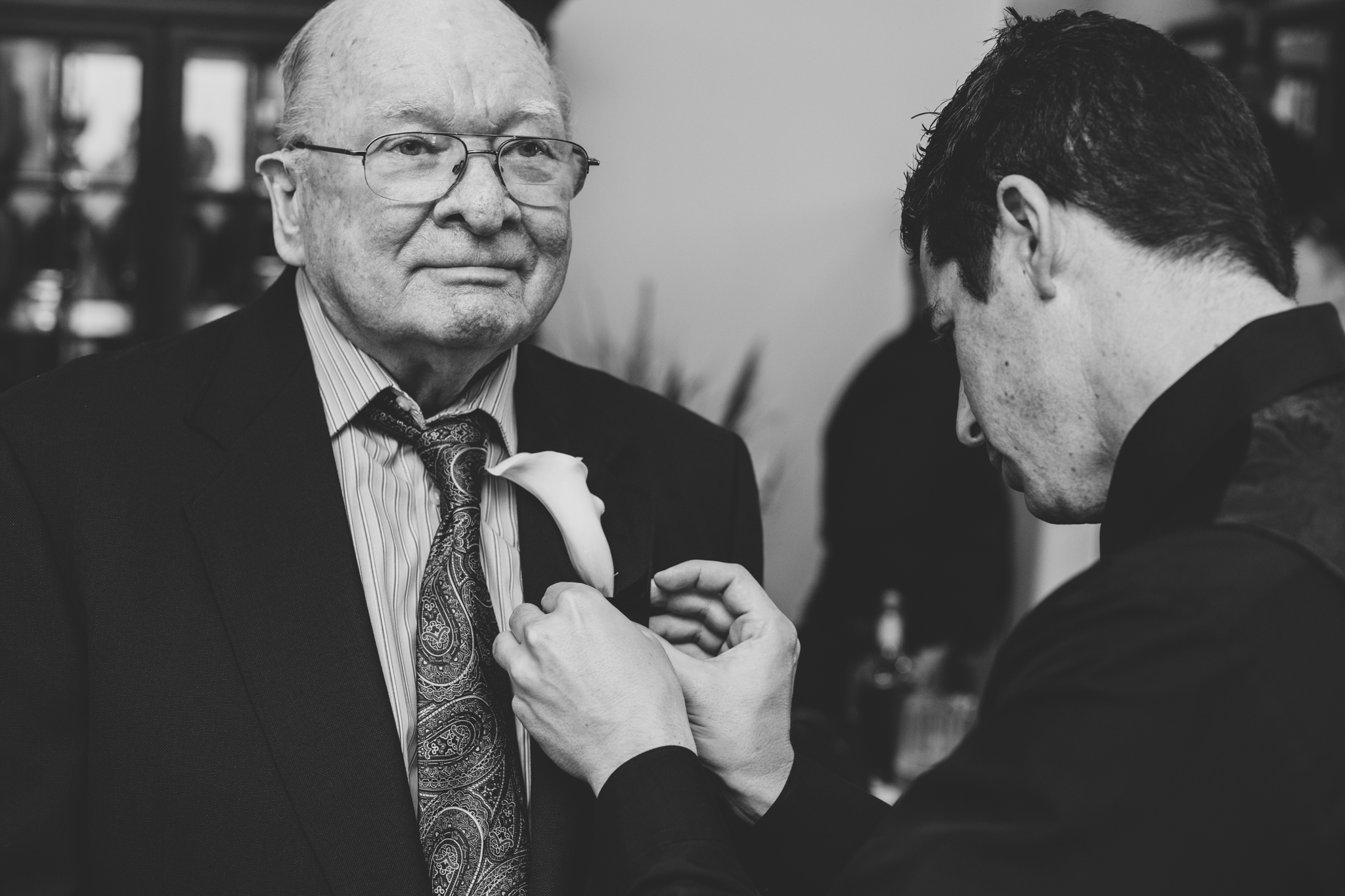 groom puts boutoniere on grandfather mj