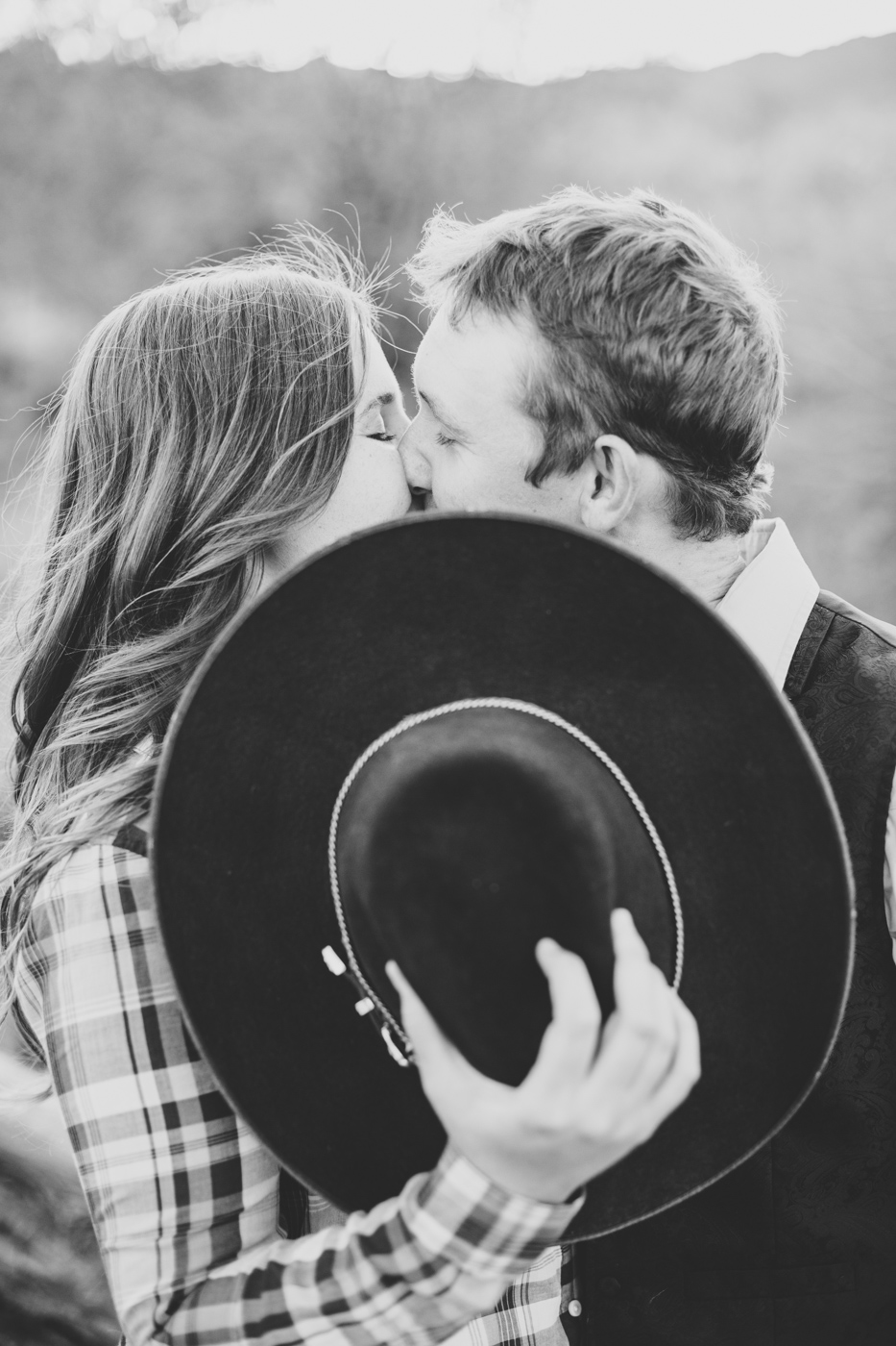 cute-kissing-behind-cowboy-hat-engagement-session-photo