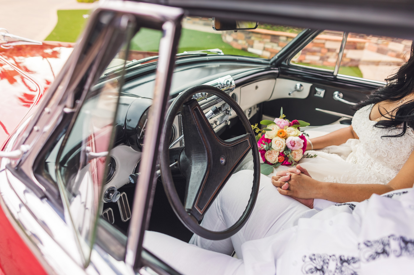 bride-and-groom-hold-hands-in-classic-car