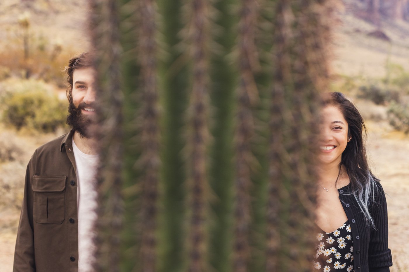 couple look at the camera separated by cactus