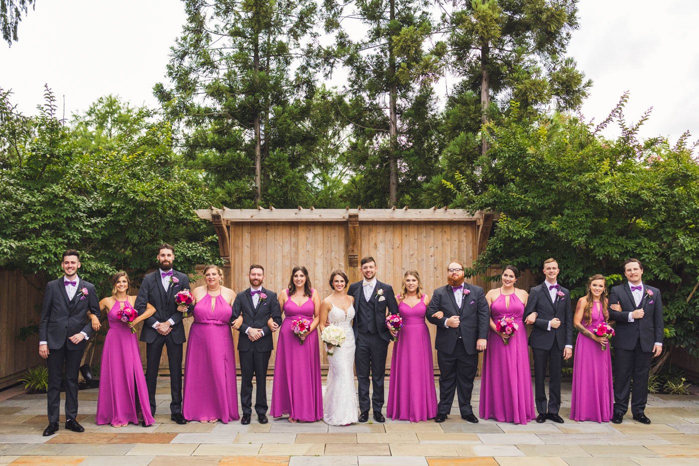 wedding party in front of wooden wall and trees