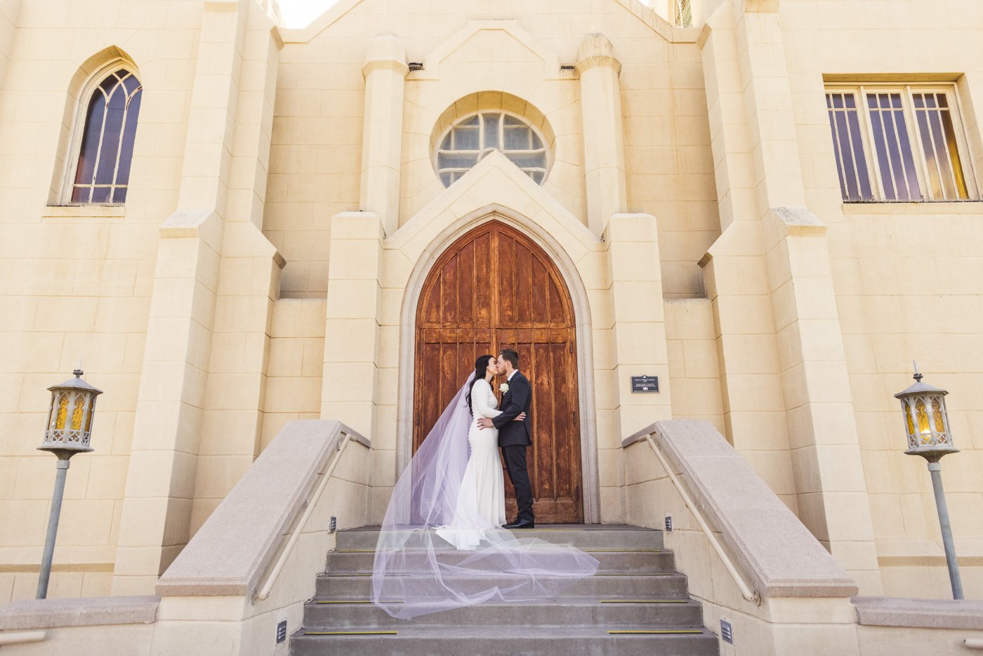 bride and groom kissing on church steps