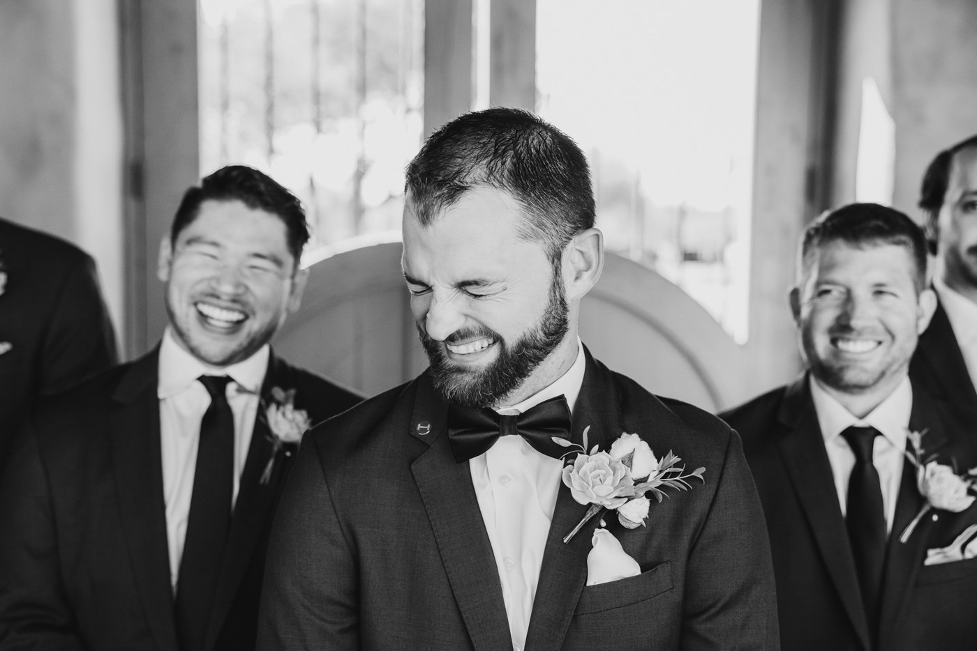 groom trying not to laugh during photo with groomsmen