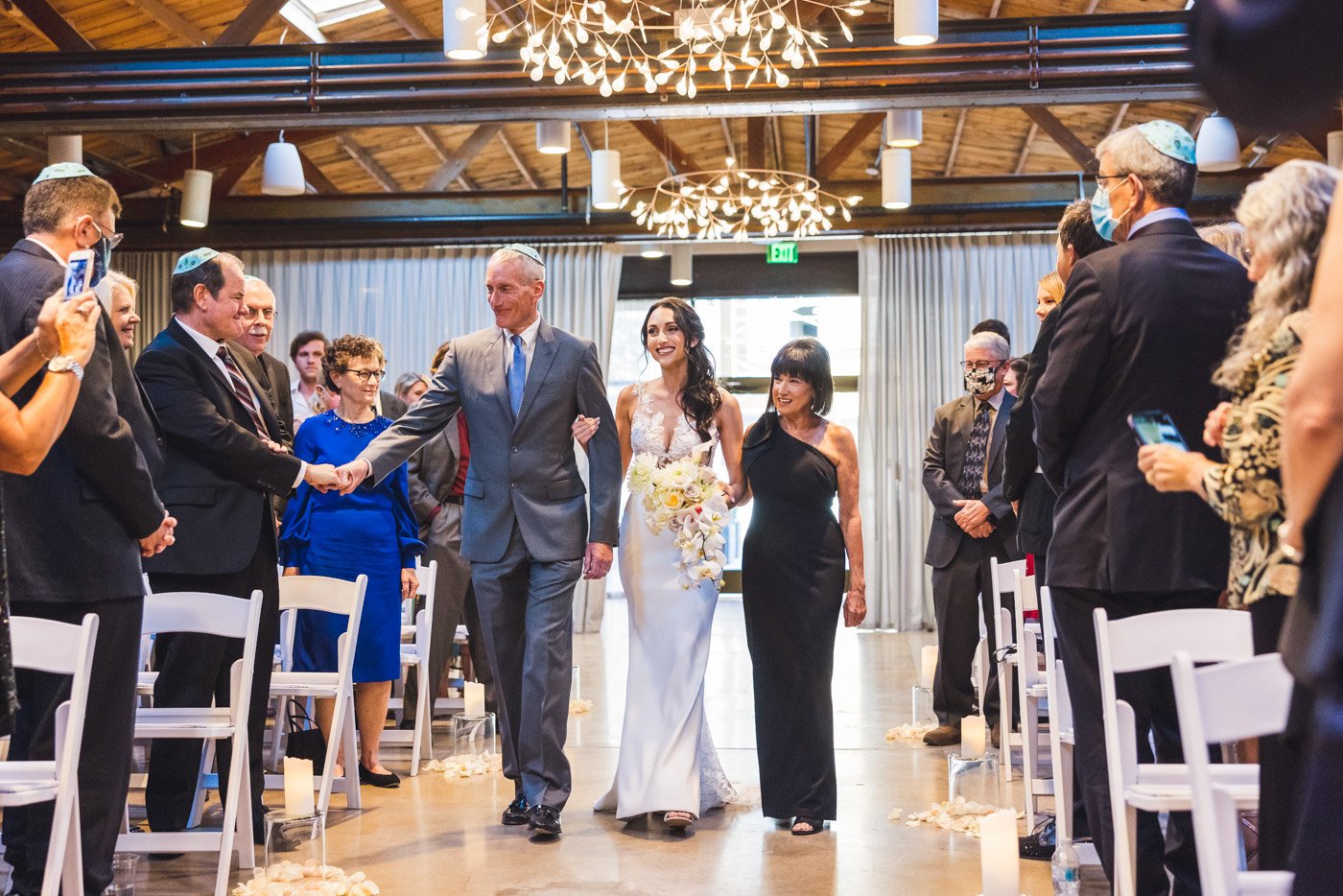 bride walked down aisle by mother and father while dad daps guest