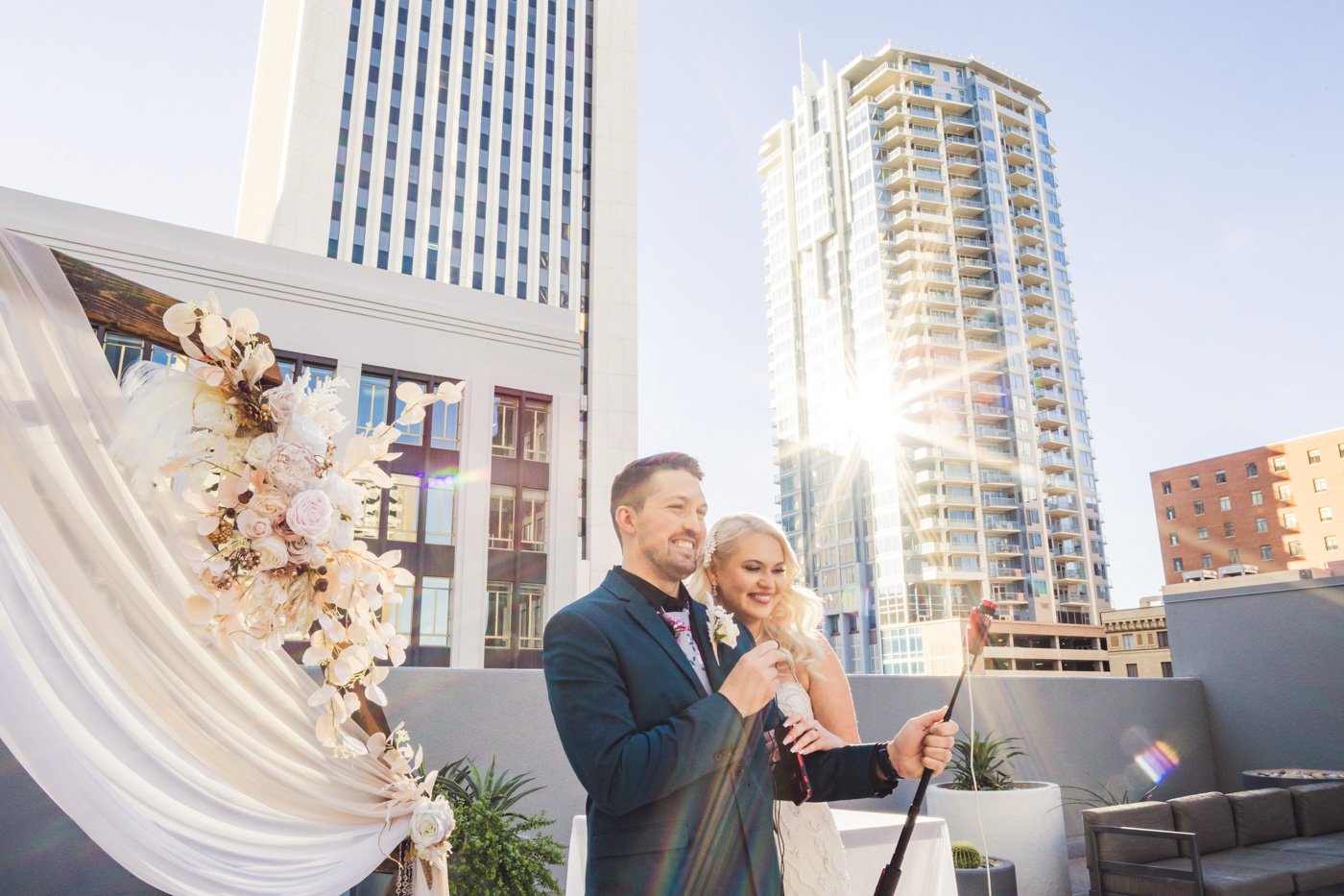 bride and groom talk to zoom guests at rooftop wedding