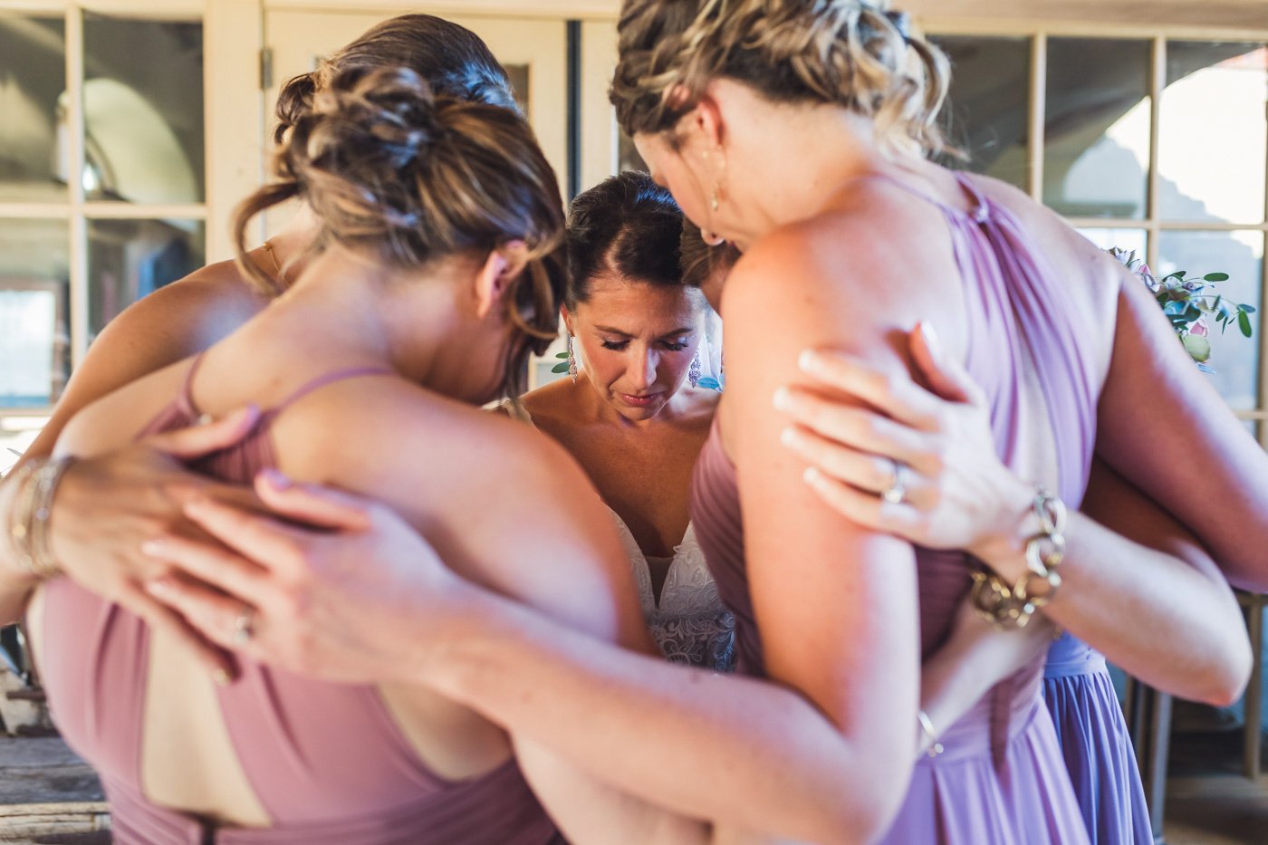bride huddled in prayer with bridesmaids before wedding ceremony