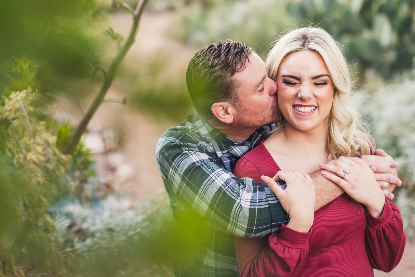 woman smiling while fiance kisses her and squeezes from behind