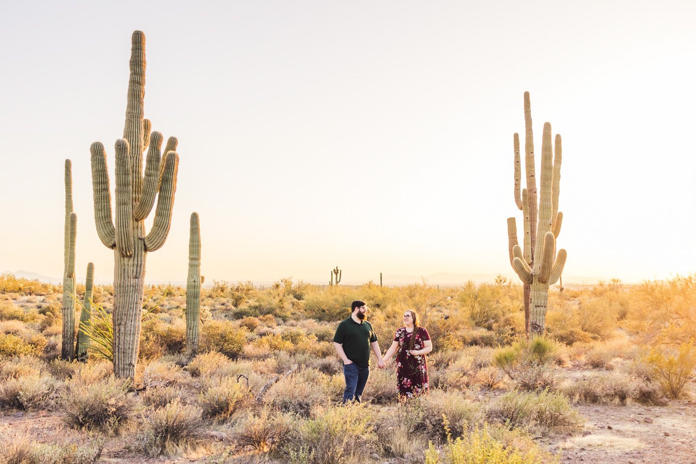 couple hold hands in arizona desert as sun lights up the scene