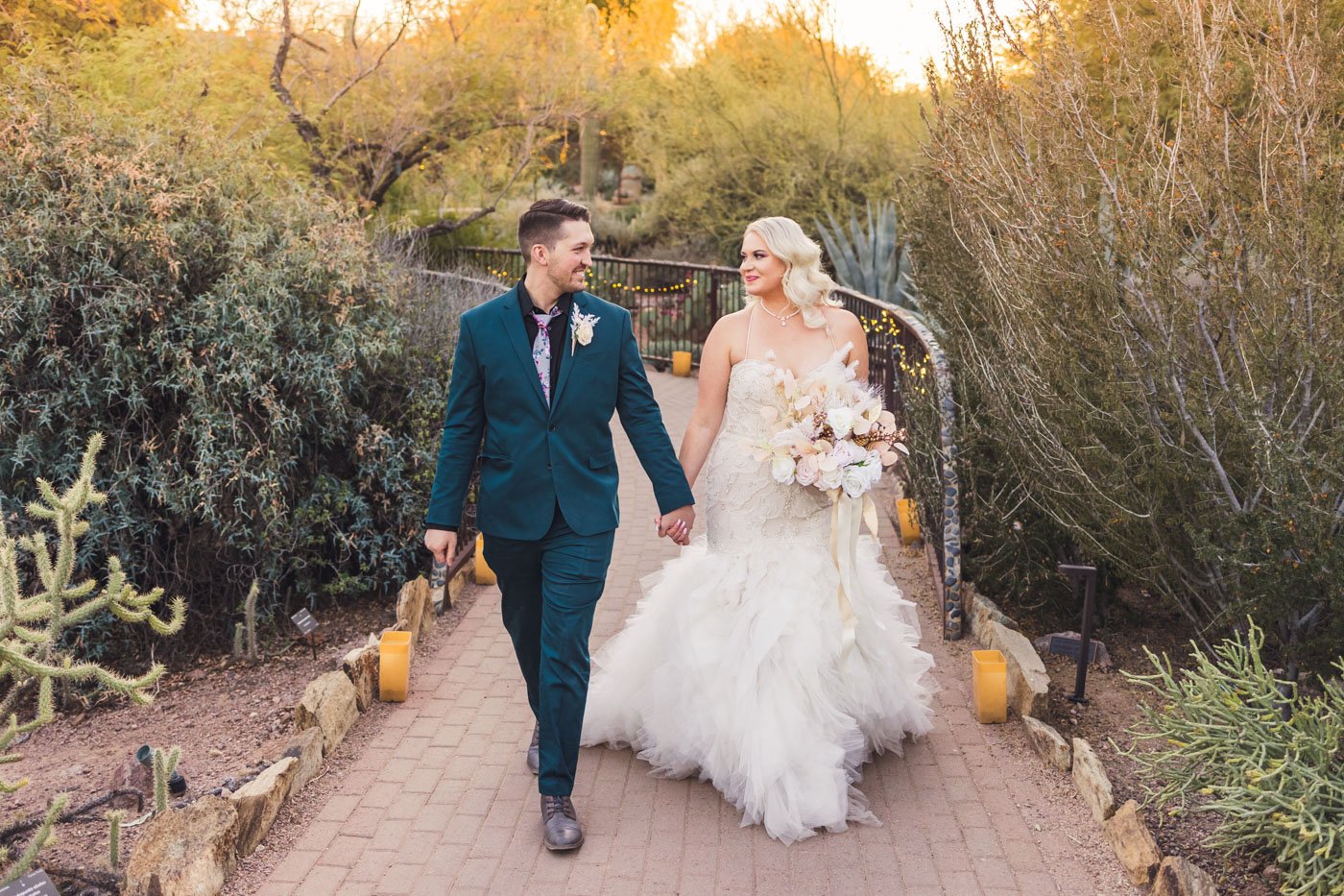 bride and groom hold hands walking through botanical garden