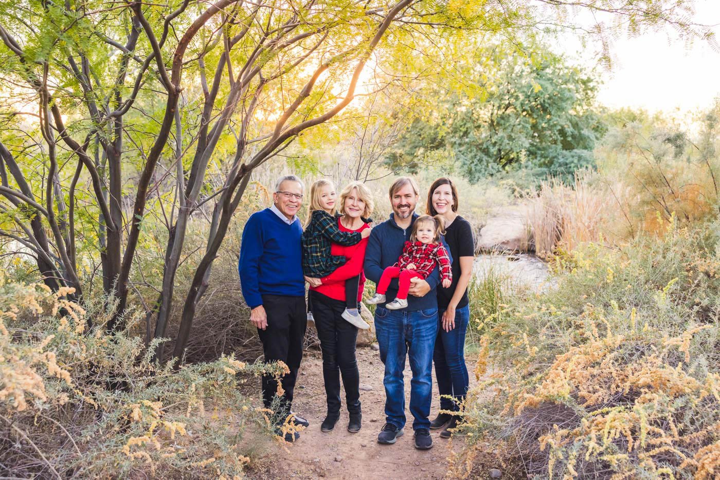 family photo in front of tree and river with sun coming through leaves