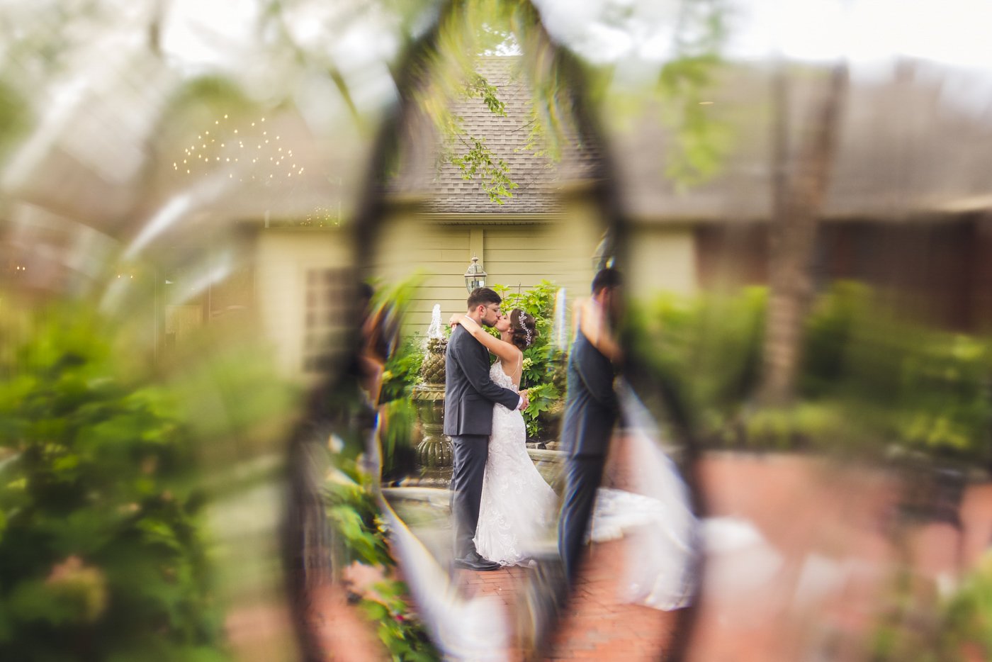 bride and groom kissing outside seen through glass in door