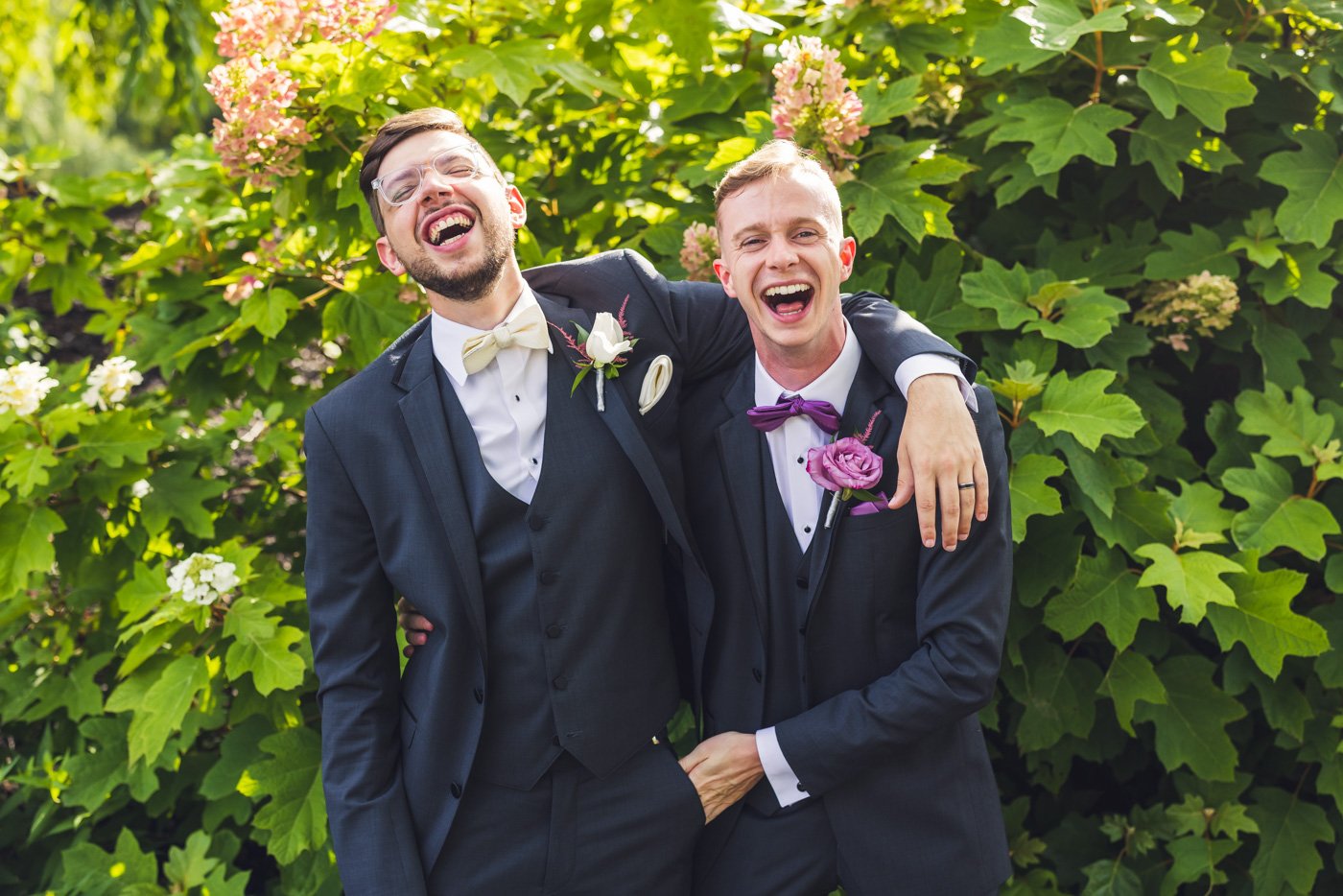 groom with arms around groomsman while both laugh