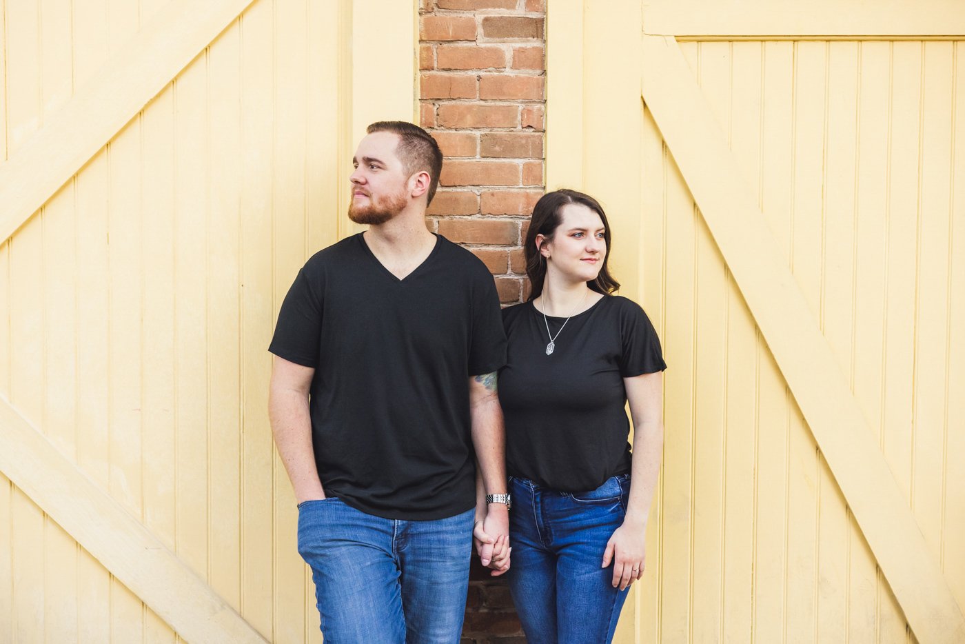 couple looking in opposite directions in front of yellow wall