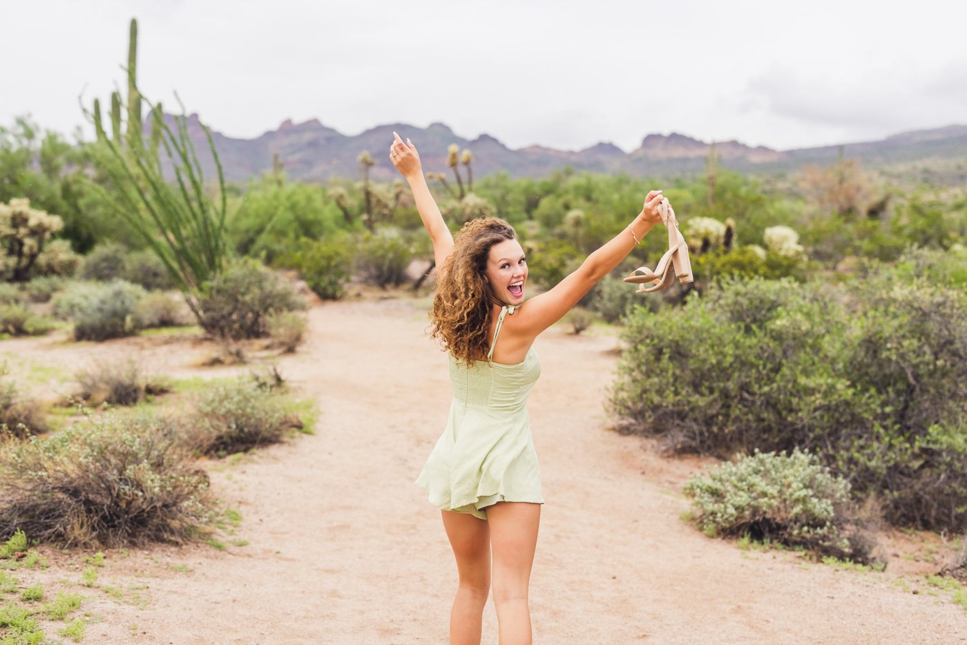 woman holding shoes running through desert