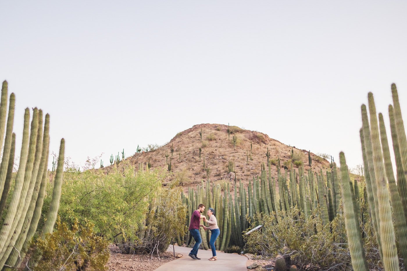 couple dancing during engagement session among cacti and mountain