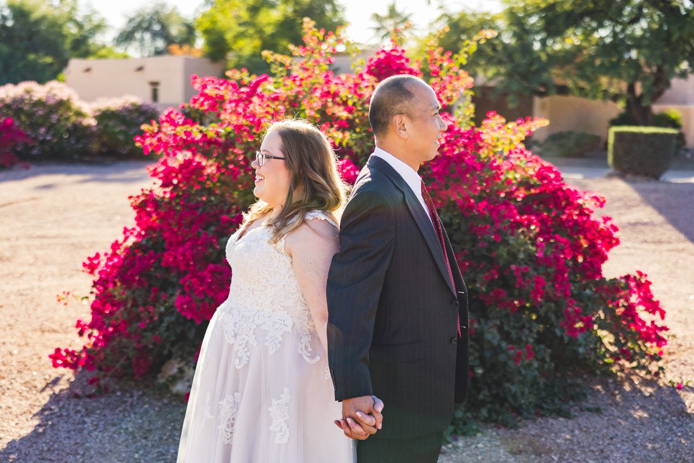 bride and groom back to back holdings hands in front of bougainvillea