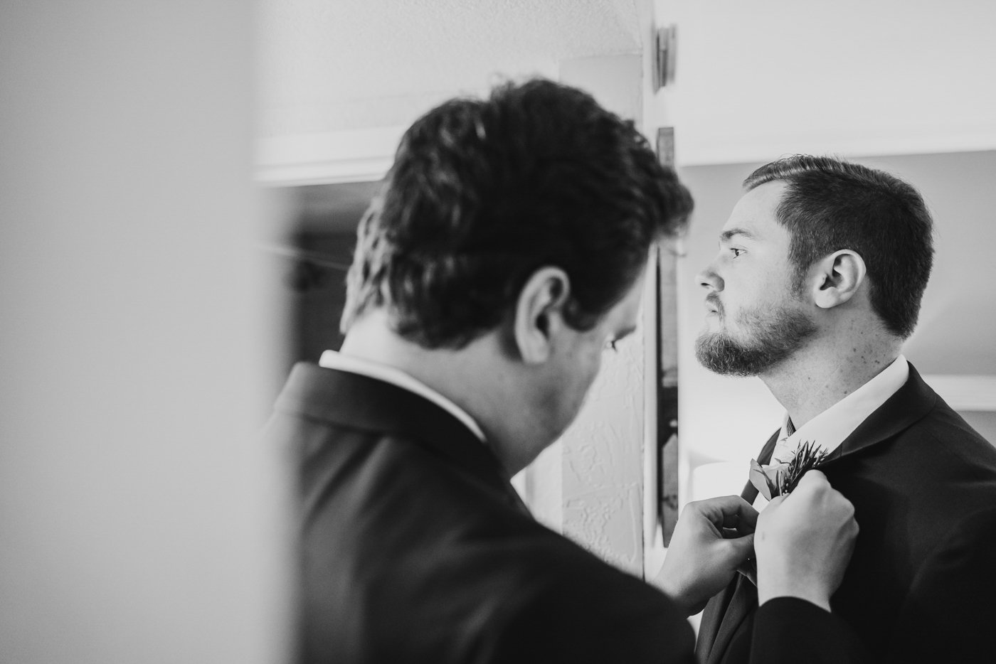 best man puts boutonniere on groom