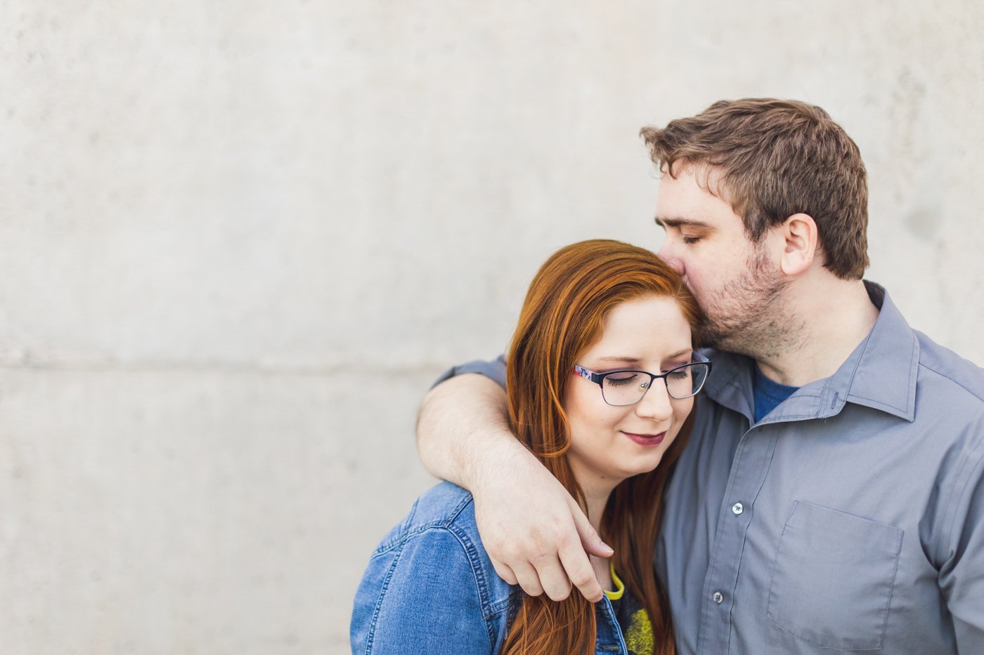man with arm around fiance kisses her head