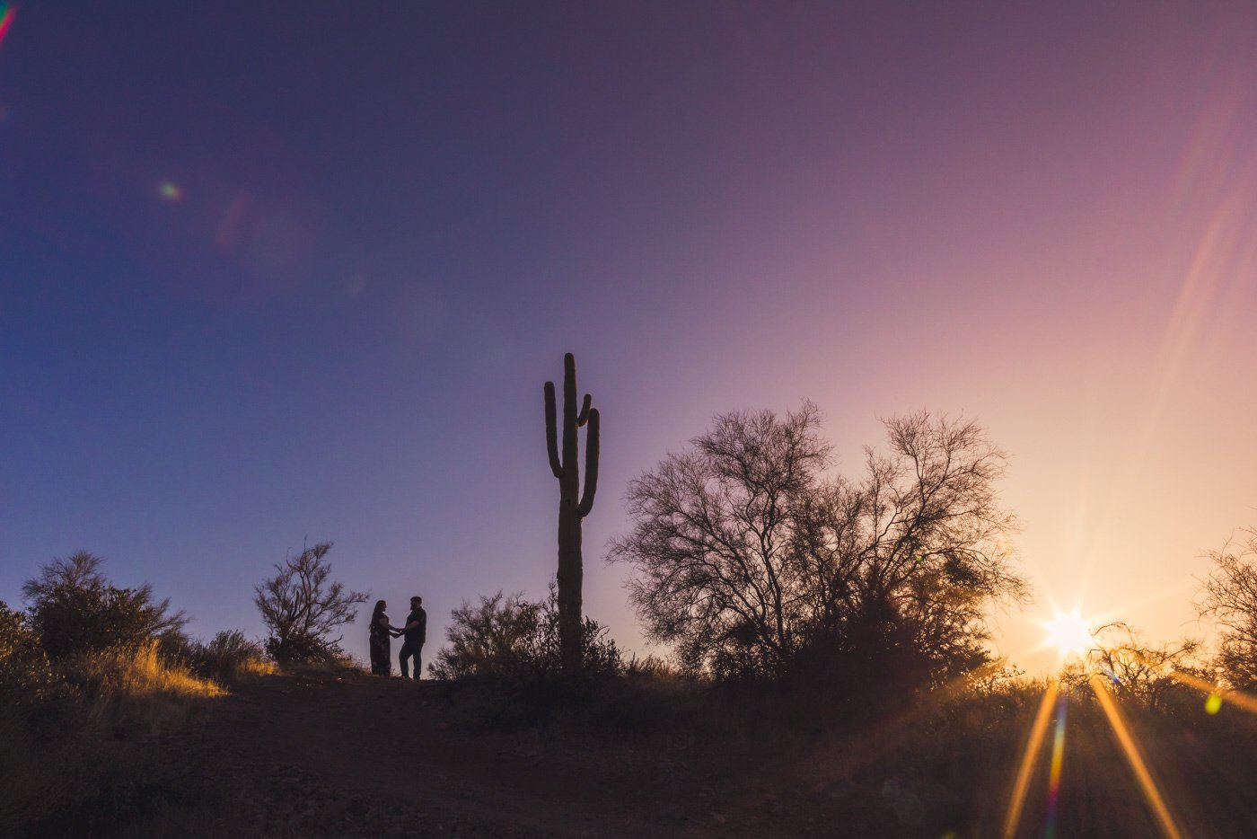 couple silhouetted against setting sun in desert