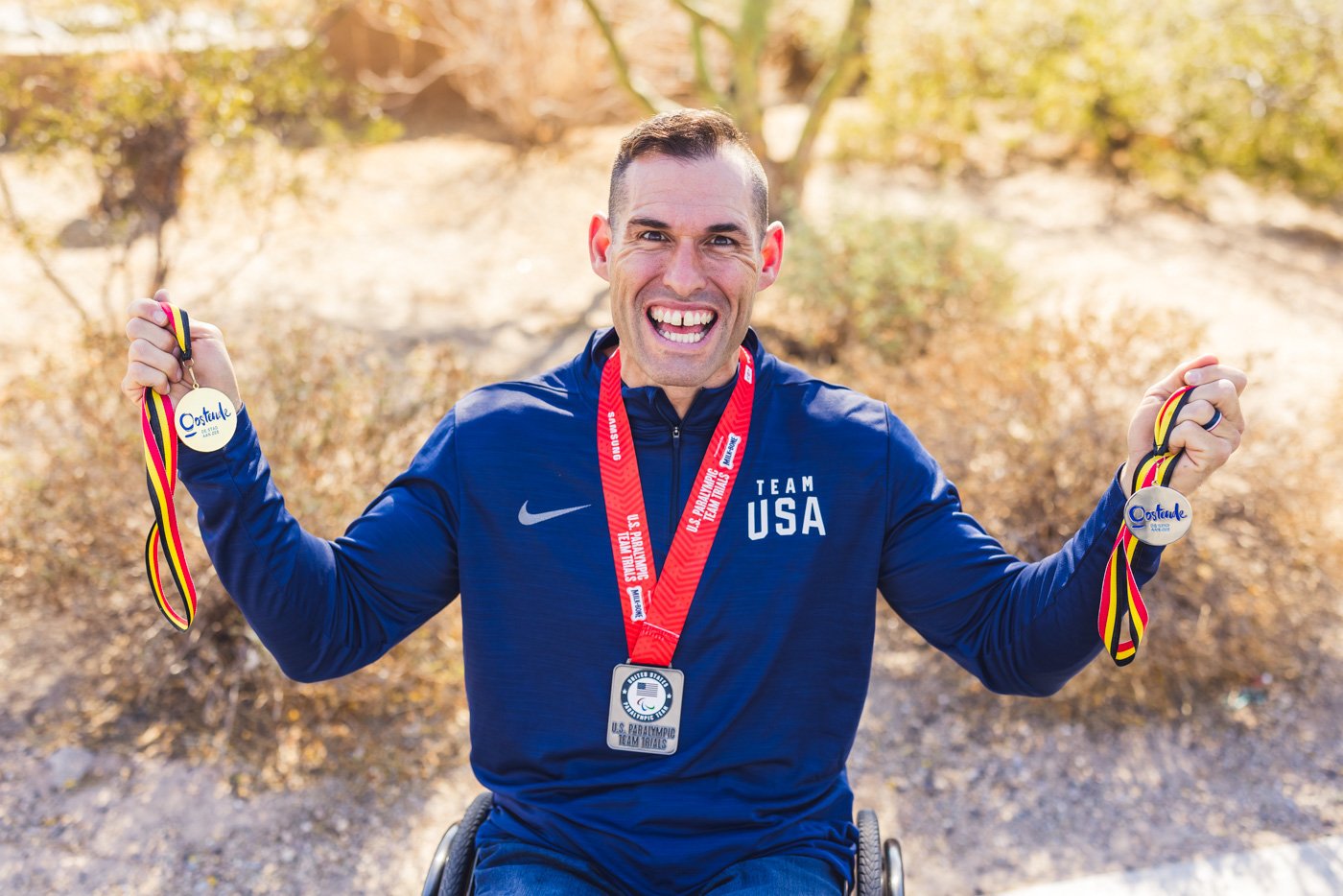 smiling hand biker ryan pinney holds his medals