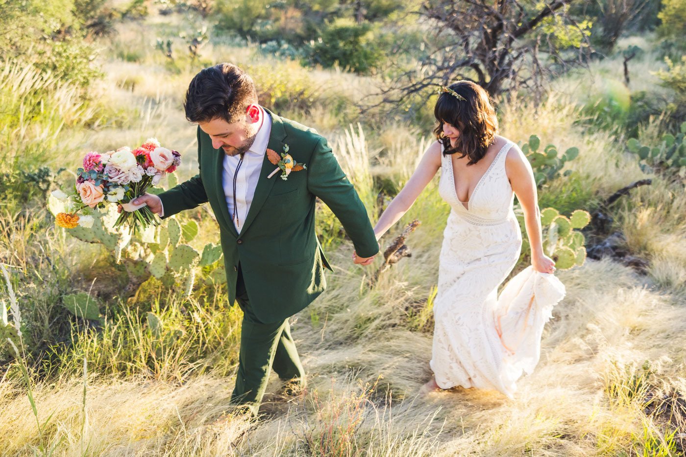 bride and groom walking through desert grass