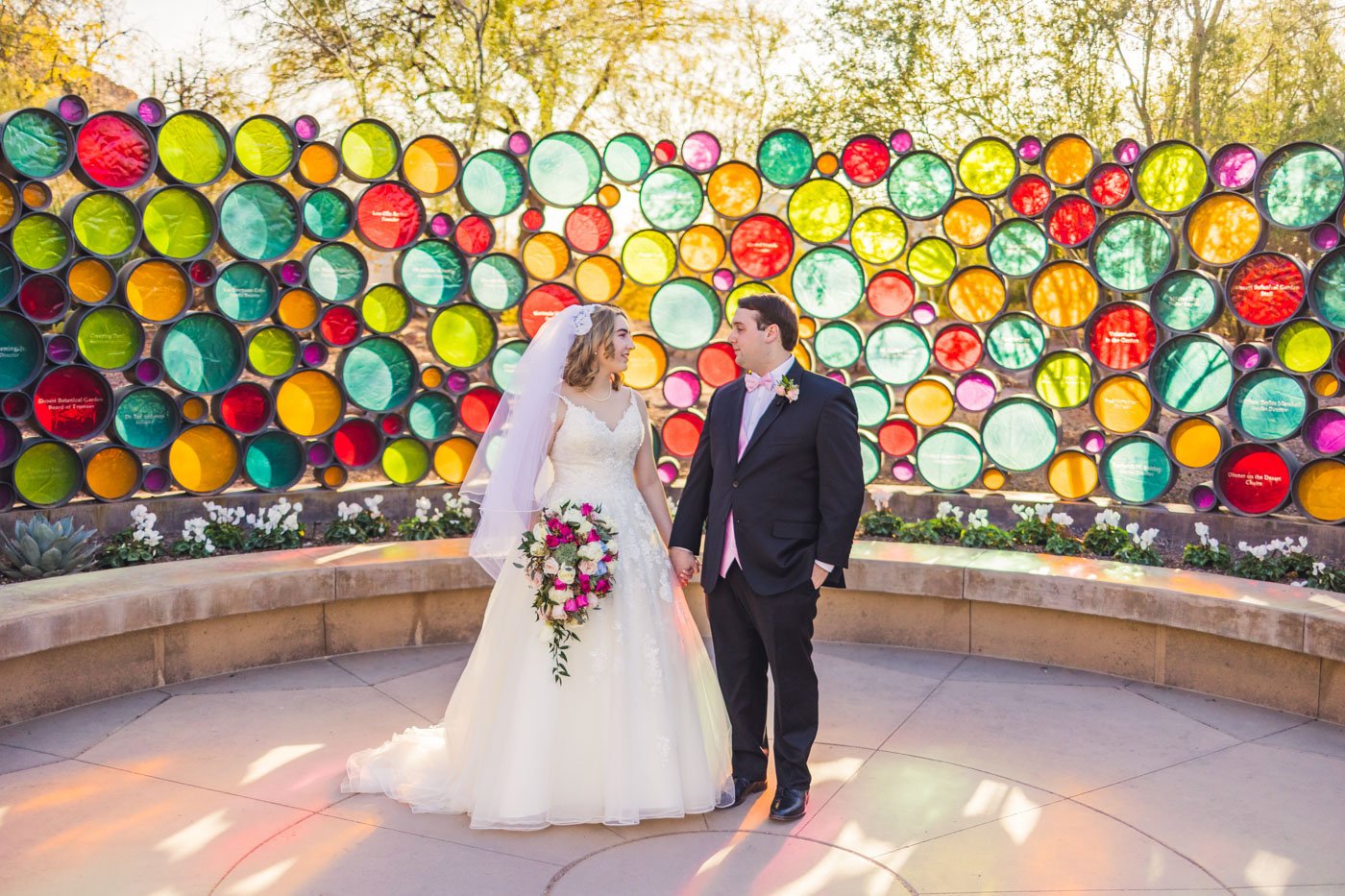 couple standing in front of colorful wall at desert botanical garden