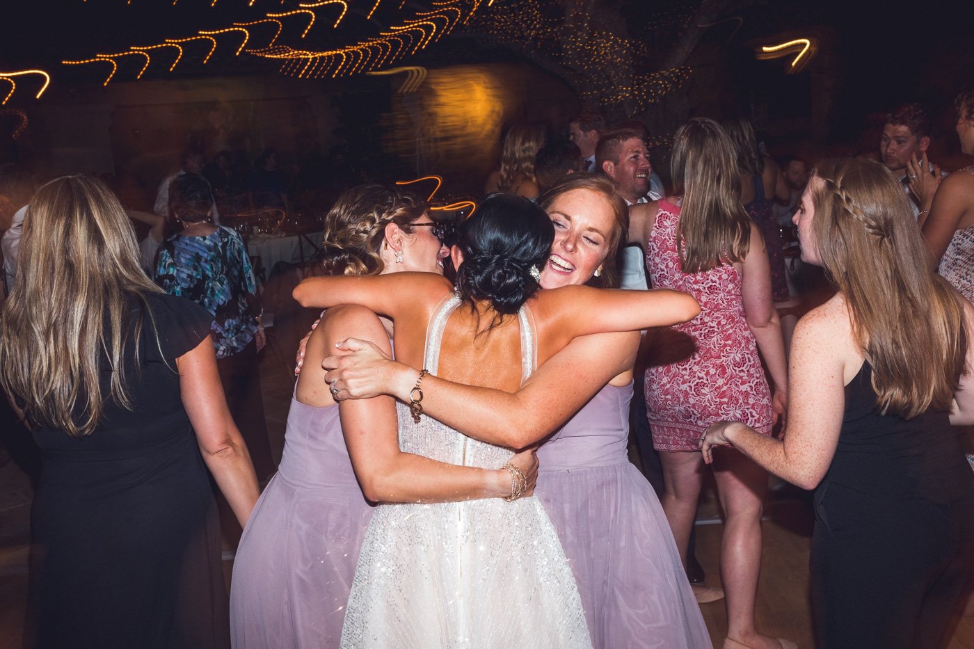 bride embraced by bridesmaids at wedding reception
