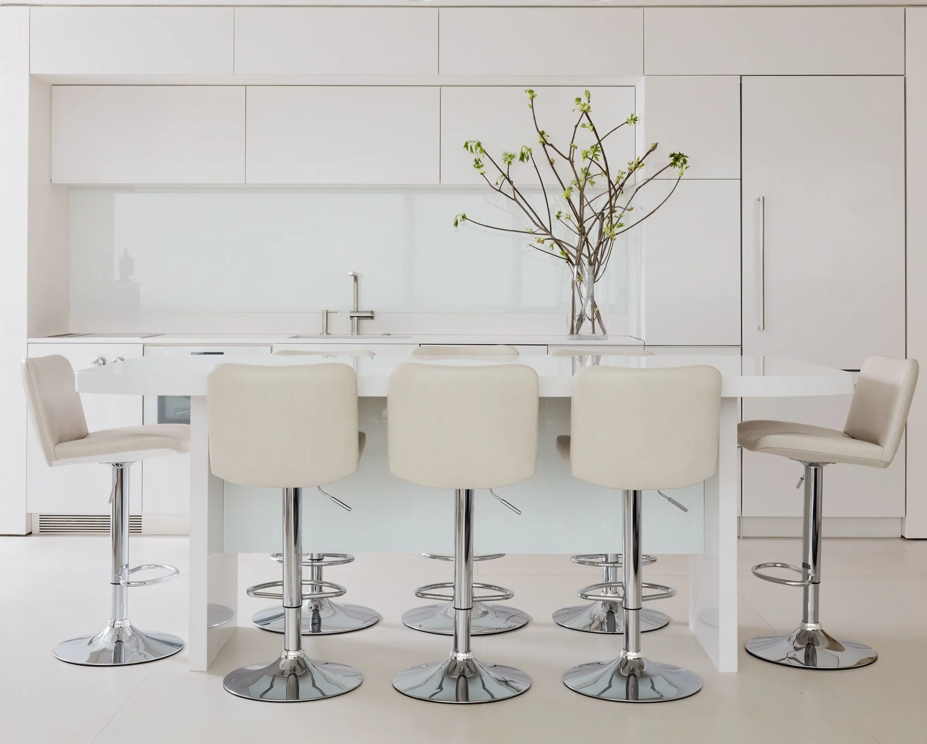 The sleek kitchen features cabinets and countertops made from Silestone in Zeus White Extreme. Custom-designed stools are covered in shagreen-imprinted leather from Jerry Pair’s Cattlelac Collection in Barley