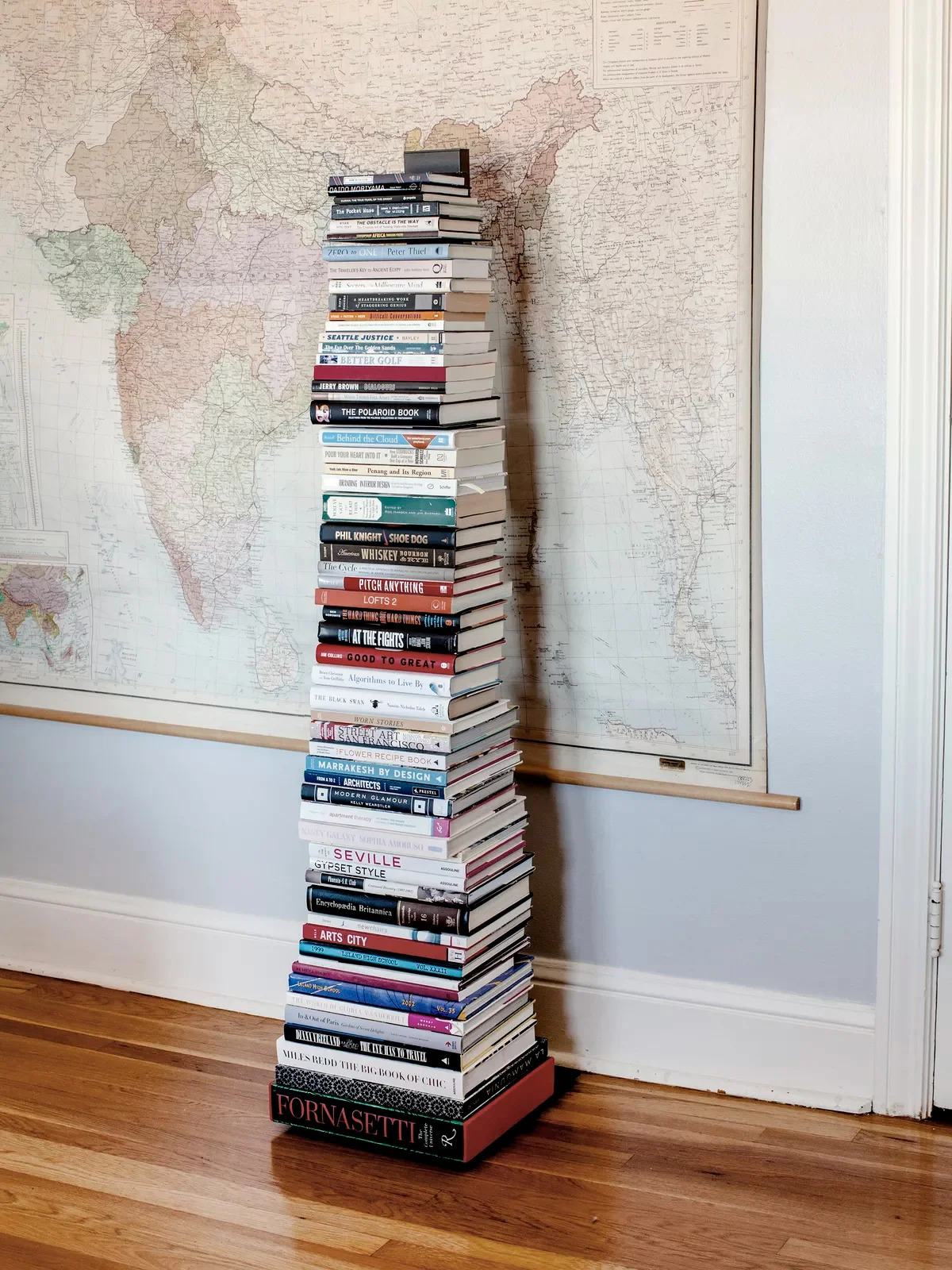 A vertical bookshelf stands in front of a vintage map.