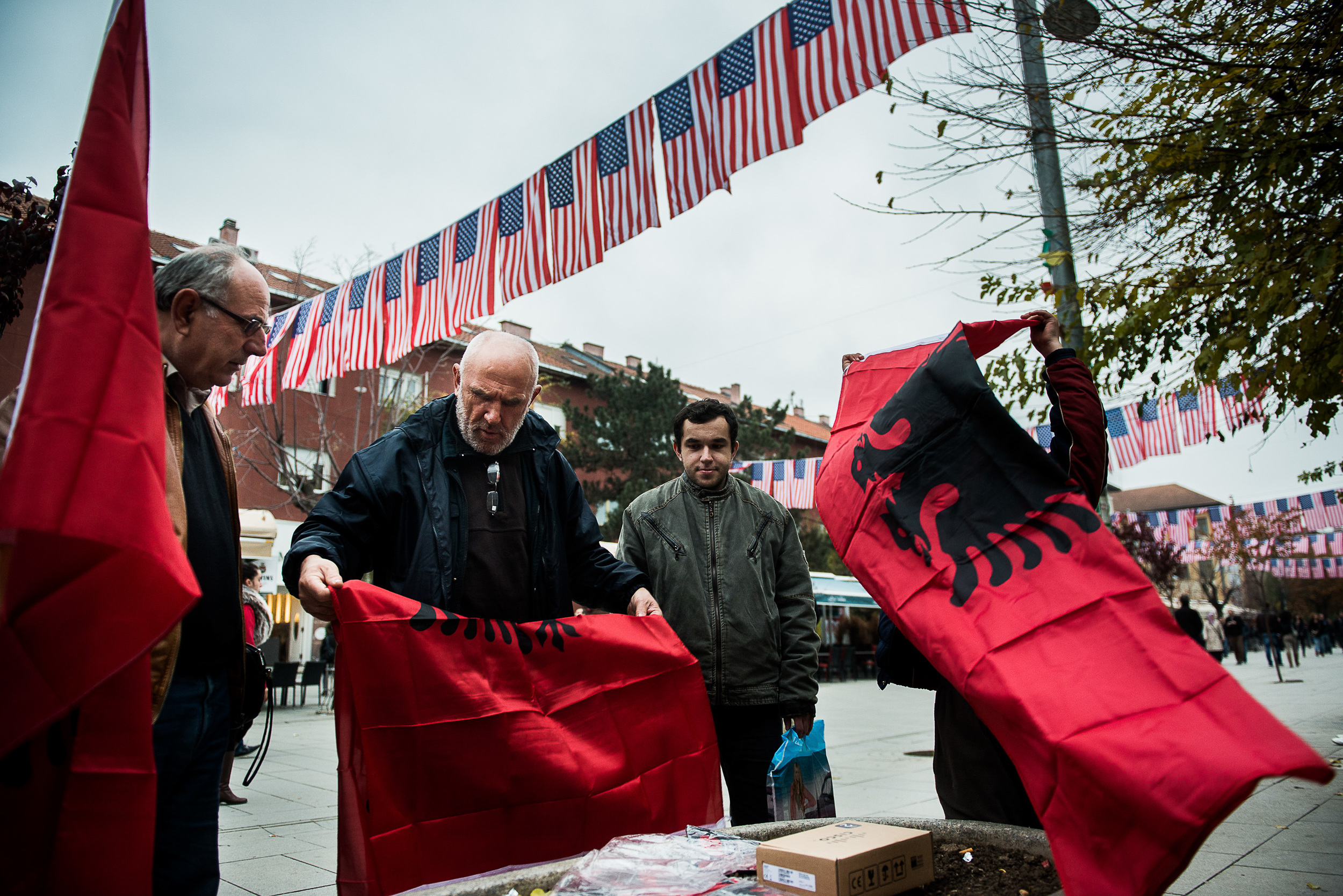 People prepare with national flags for the 100th anniversary of Albania in the main street of Pristina, Kosovo.