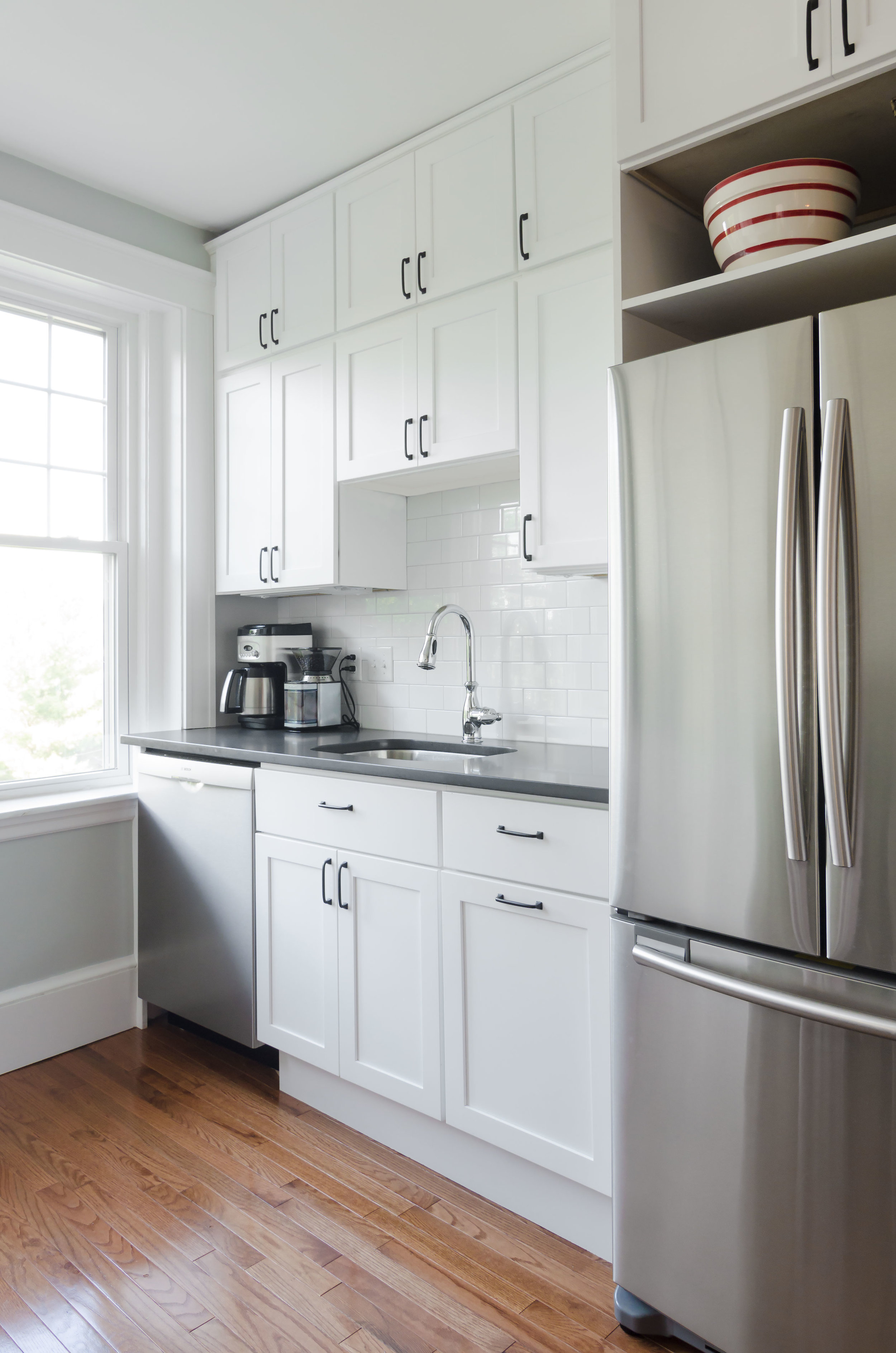 Jamaica Plain, MA -- "Sunny White" Kitchen. A gut renovation and space reconfiguration, including new cabinets, counters, tile backsplash, plumbing, lighting and flooring. A narrow, separate pantry was removed to create an airy workspace and storage. Design by the homeowner and Bailey•Davol•Studio•Build.