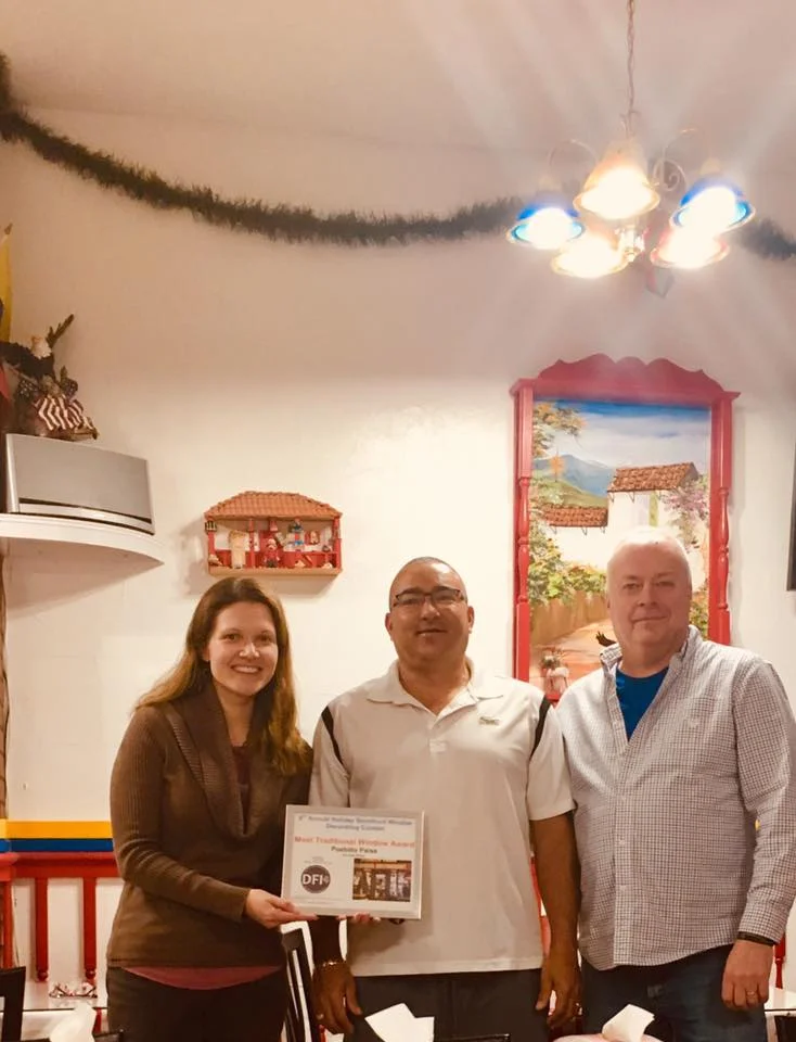 David Blais (right), Director of Daniel’s Table and Co-owner Foodie Cafe, presents the Most Traditional Storefront Award to Ignacio Jaramillo (center), co-owner of Pueblito Paisa .
