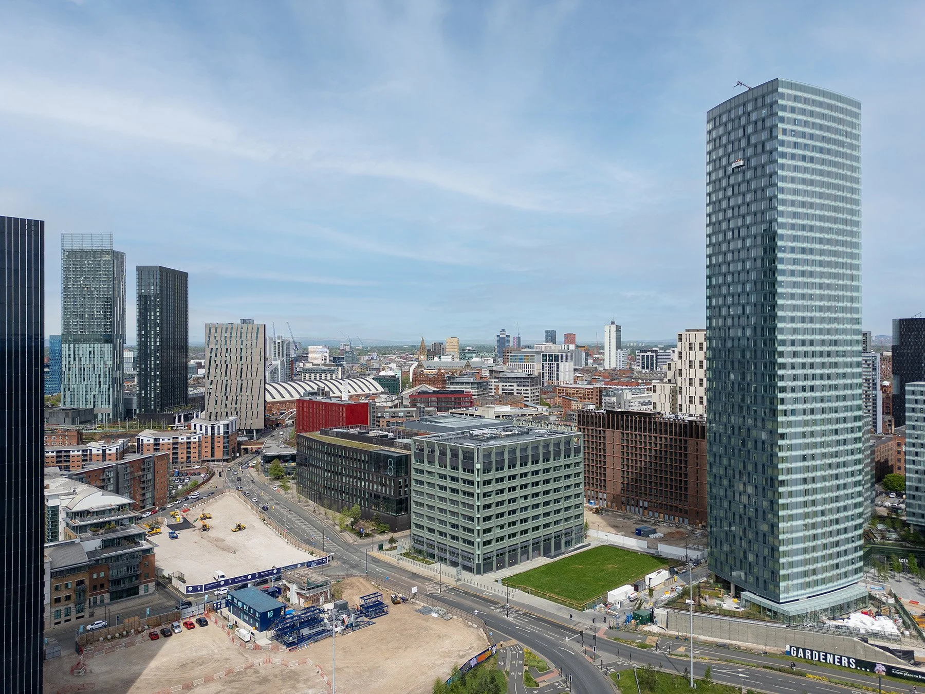 City skyline with tall modern skyscrapers, some under construction, and a clear blue sky.